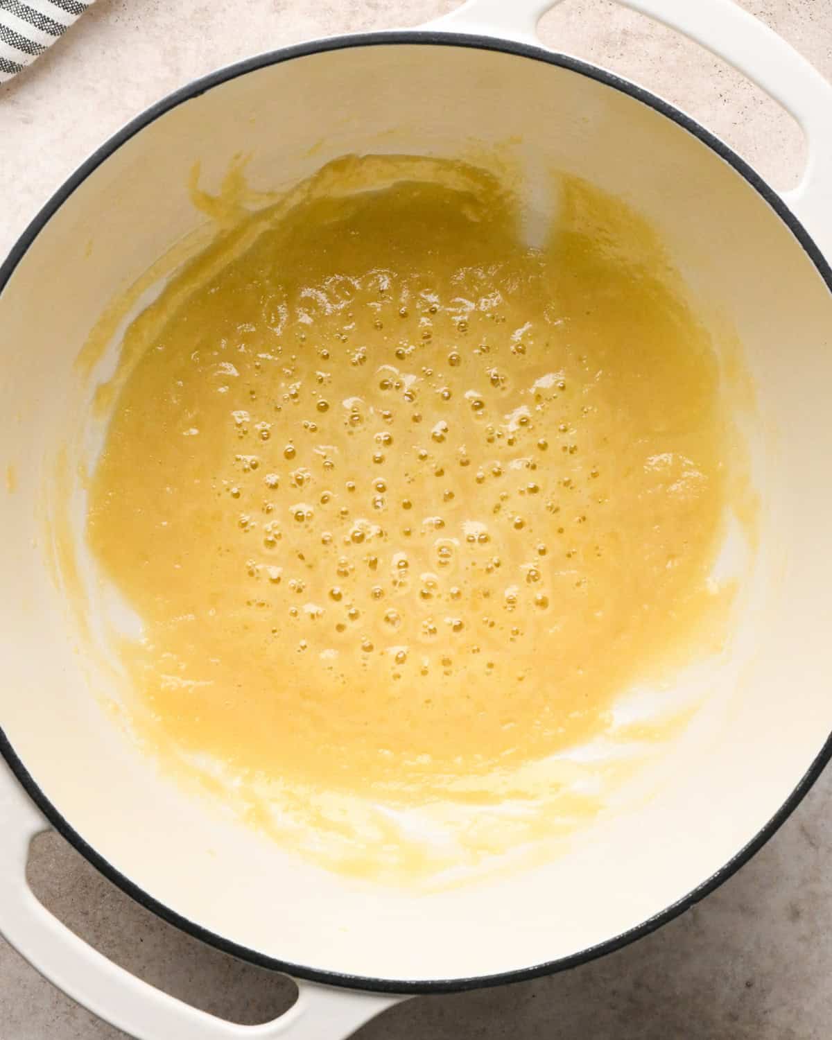 Making broccoli macaroni and cheese (mac and cheese): overhead photo of homemade cheese sauce being brought to a simmer in a large pot.