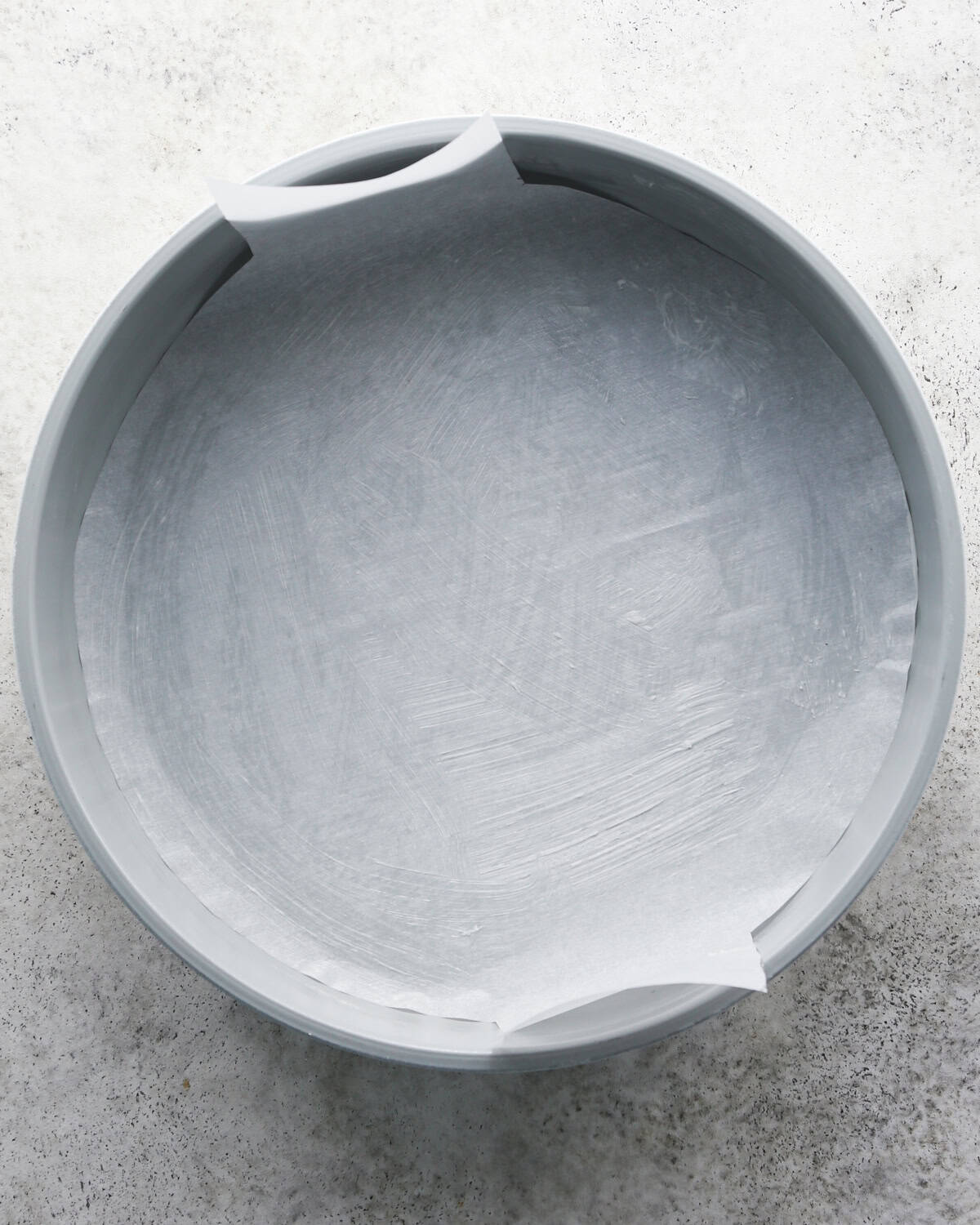 a round silver cake plate lined with parchment paper and greased on a gray background