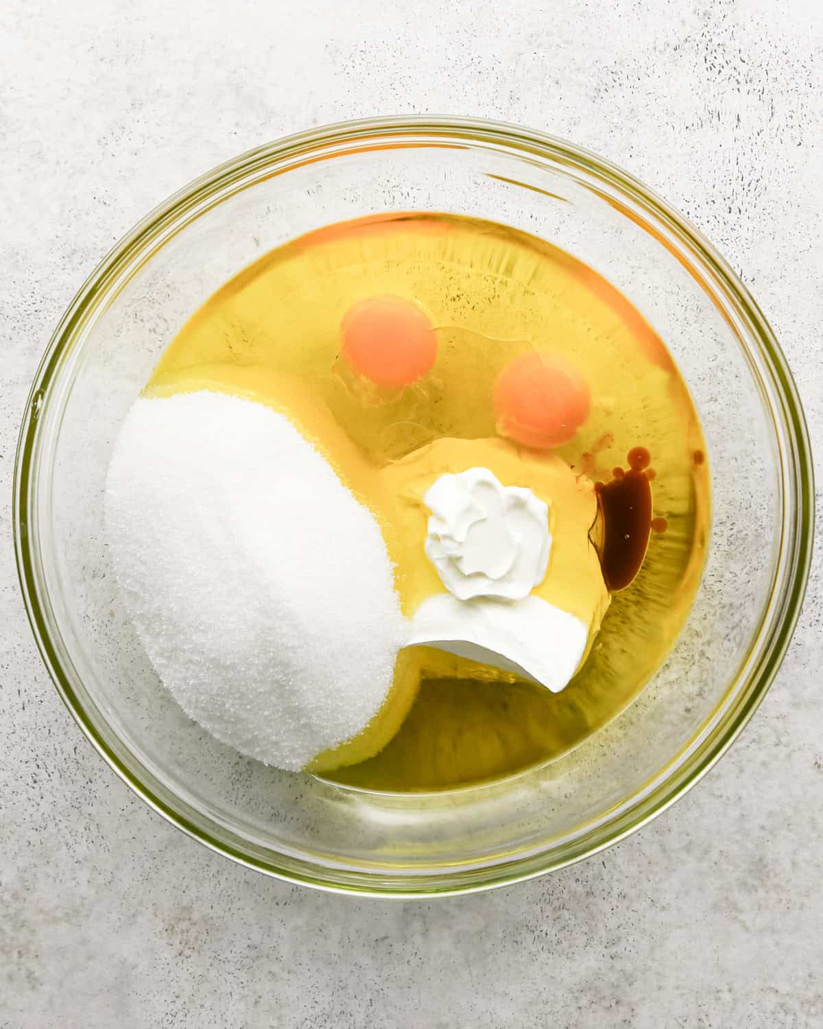 making chocolate olive oil cake - eggs, olive oil, sugar, sour cream and vanilla in a bowl before whisking