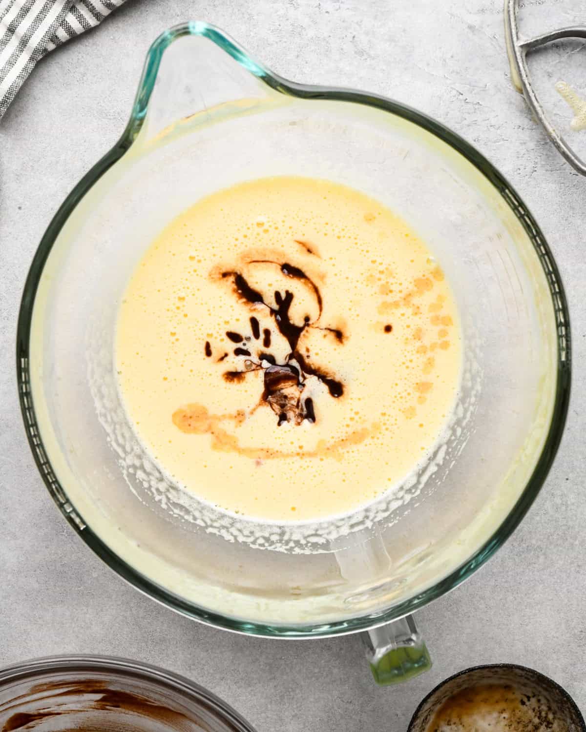 making cookie dough brownies - melted chocolate, butter and vanilla added to the beaten egg mixture in a glass mixing bowl before mixing