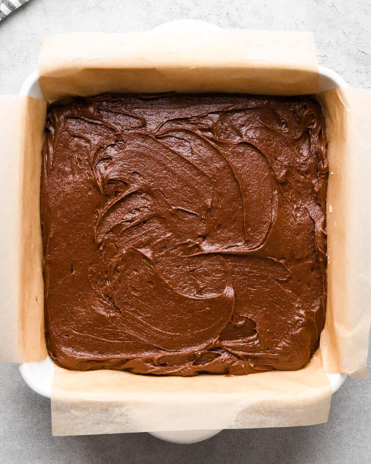 cookie dough brownie batter spread into the parchment lined baking dish before baking