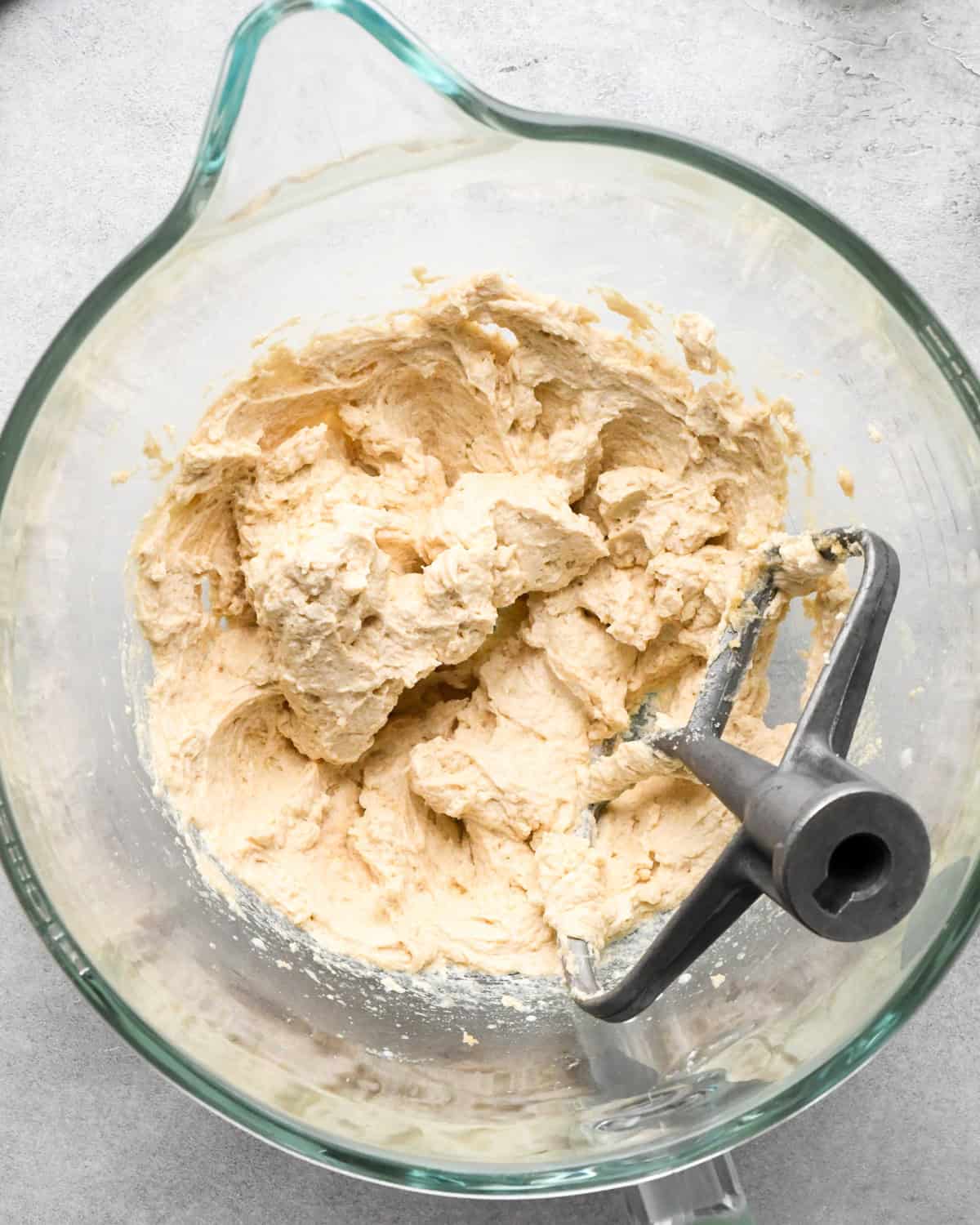 making cookie dough brownies - wet ingredient mixture in a glass mixing bowl with the paddle attachment in the bowl. 