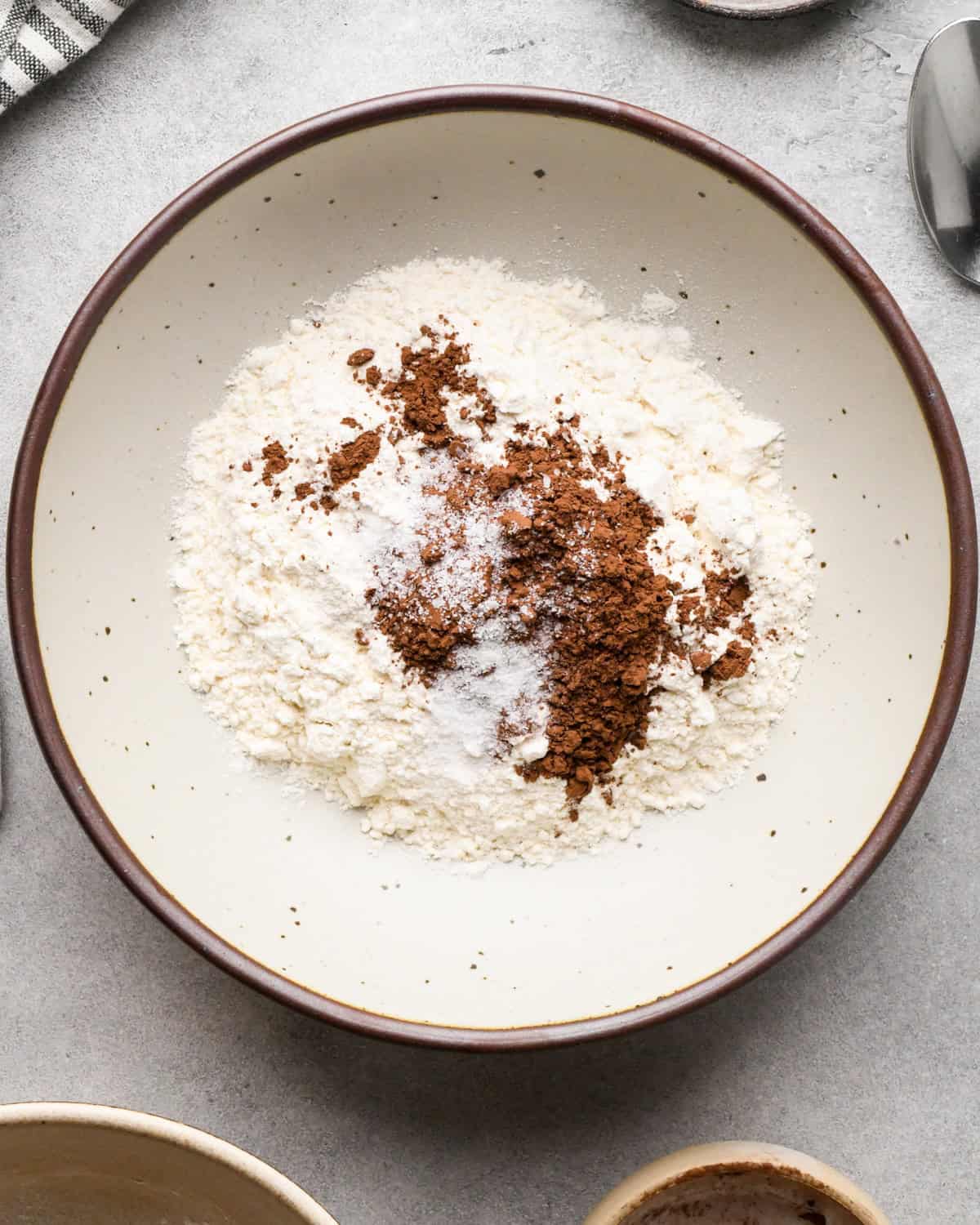 making cookie dough brownies - flour, cocoa powder and salt in a white ceramic bowl with a brown rim before mixing
