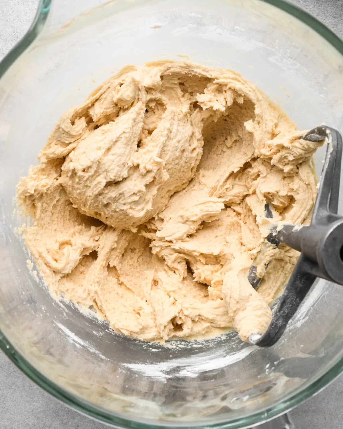 making cookie dough brownies - cookie dough without chocolate chips in a glass mixing bowl with the paddle attachment in the bowl 