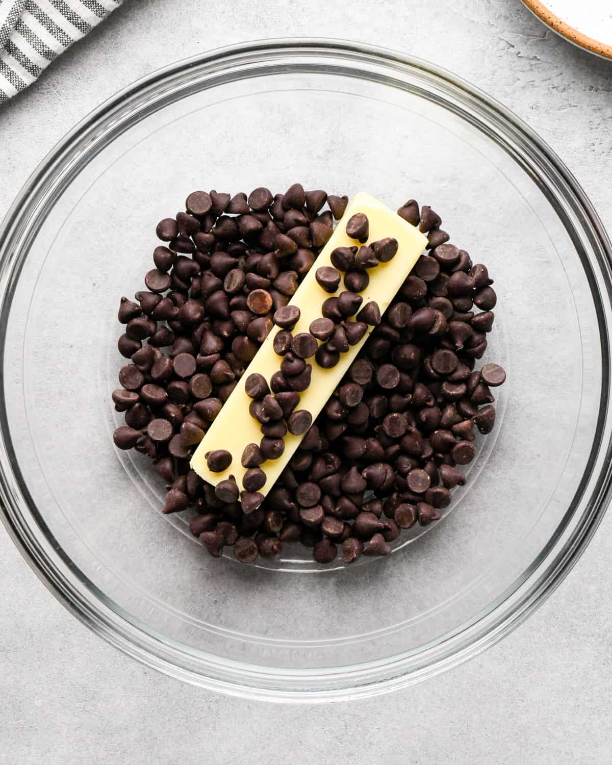 making cookie dough brownies - a stick of butter and chocolate chips in a glass bowl 
