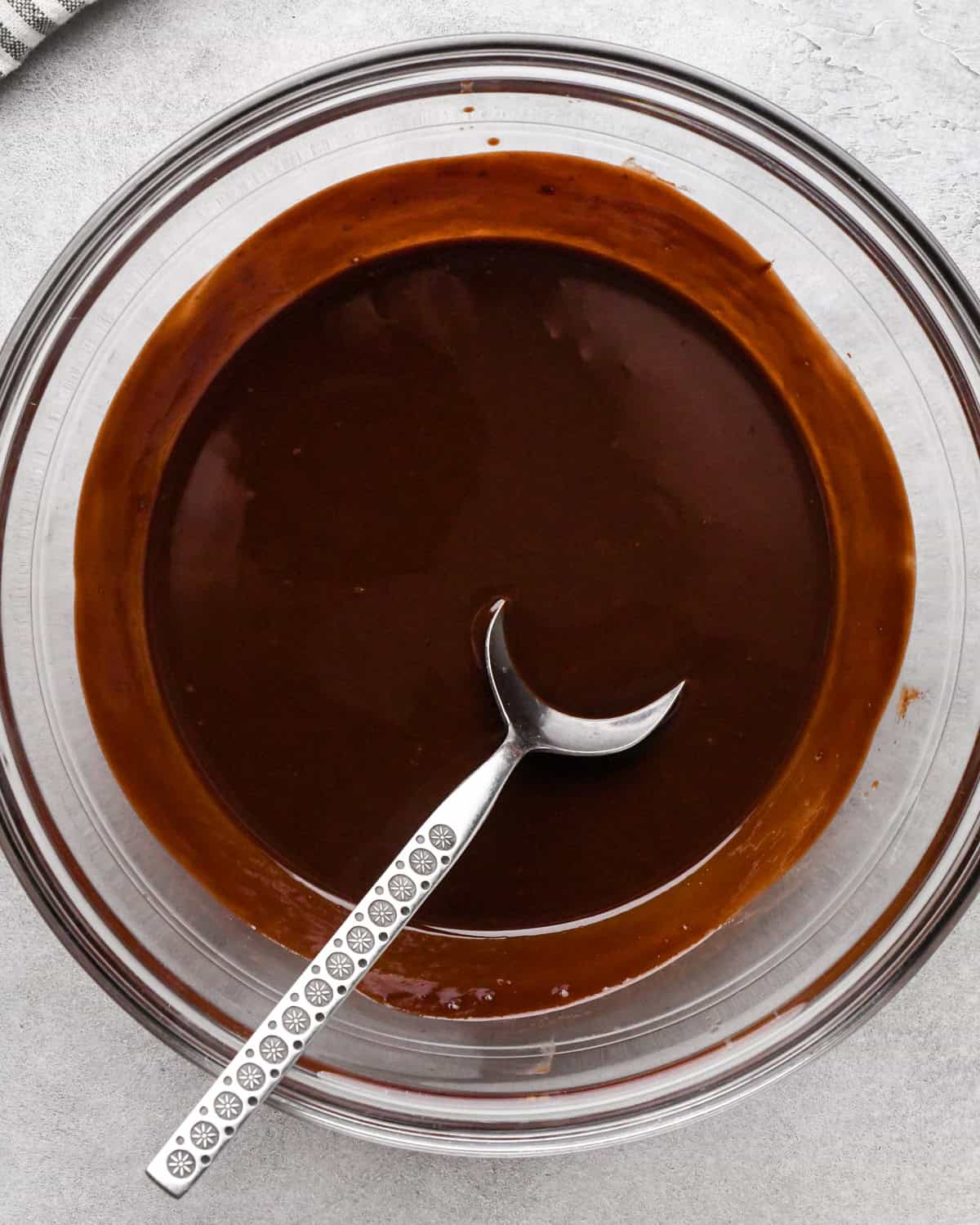 making cookie dough brownies - melted chocolate and butter in a glass bowl with a metals spoon