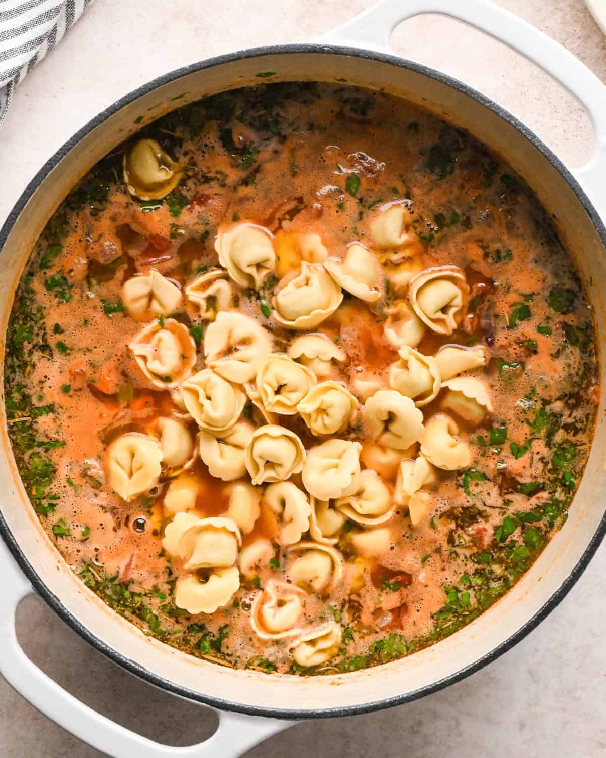 Making sausage tortellini soup: overhead photo of all ingredients including tortellini added to a large pot.