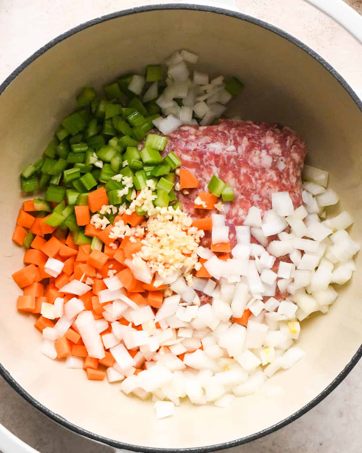 Making sausage tortellini soup: overhead photo of meat, vegetables, and garlic added to a pot and ready to be cooked.