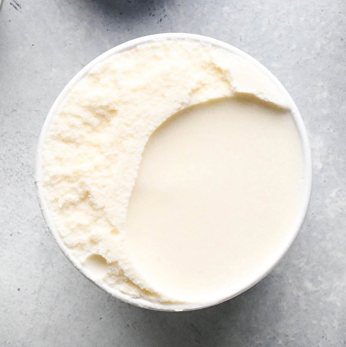 overhead photo of a pint of vanilla ice cream with the lid off softening to make a shamrock shake