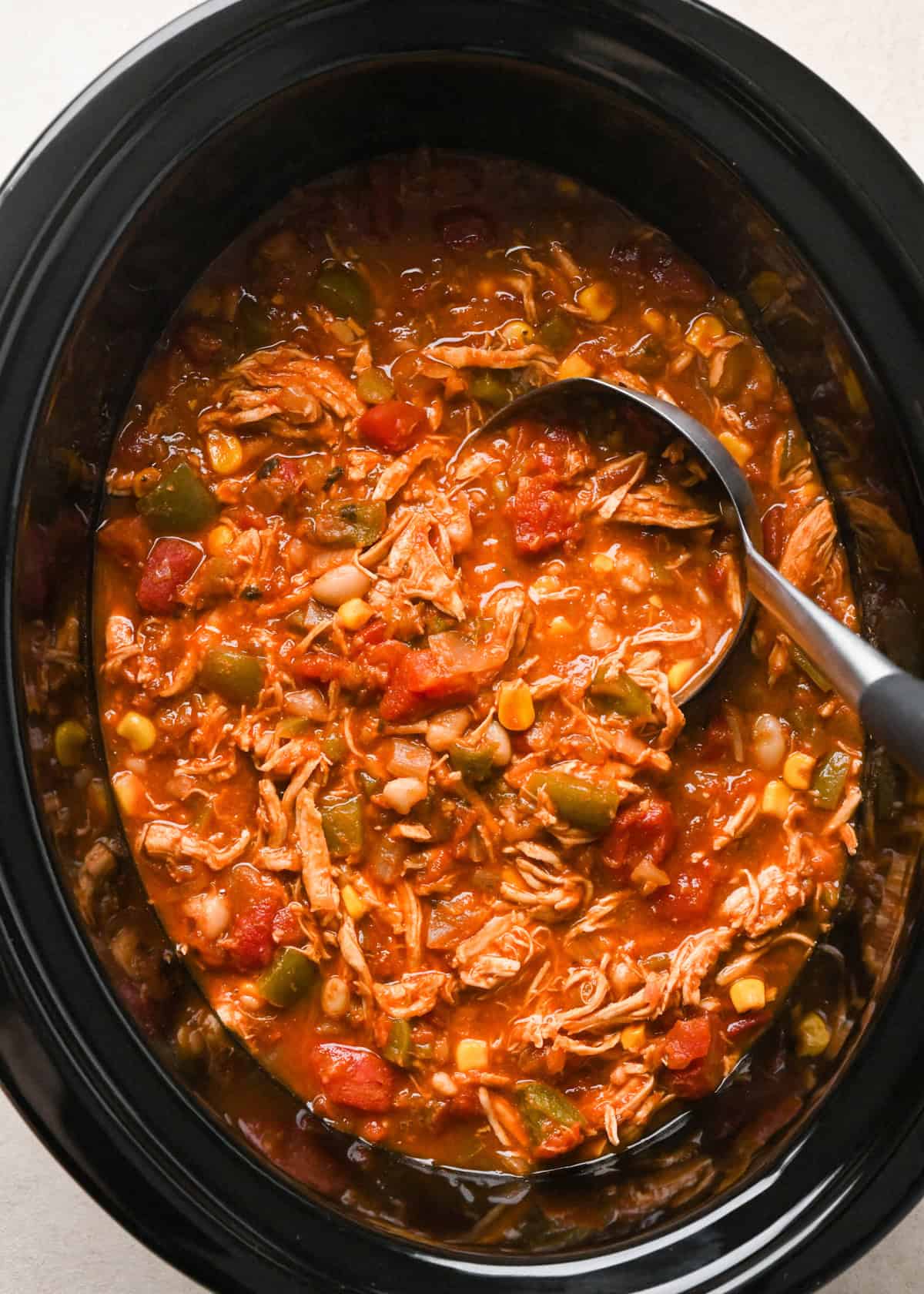 a ladle taking a scoop of Chicken Chili out of the container of a slow cooker