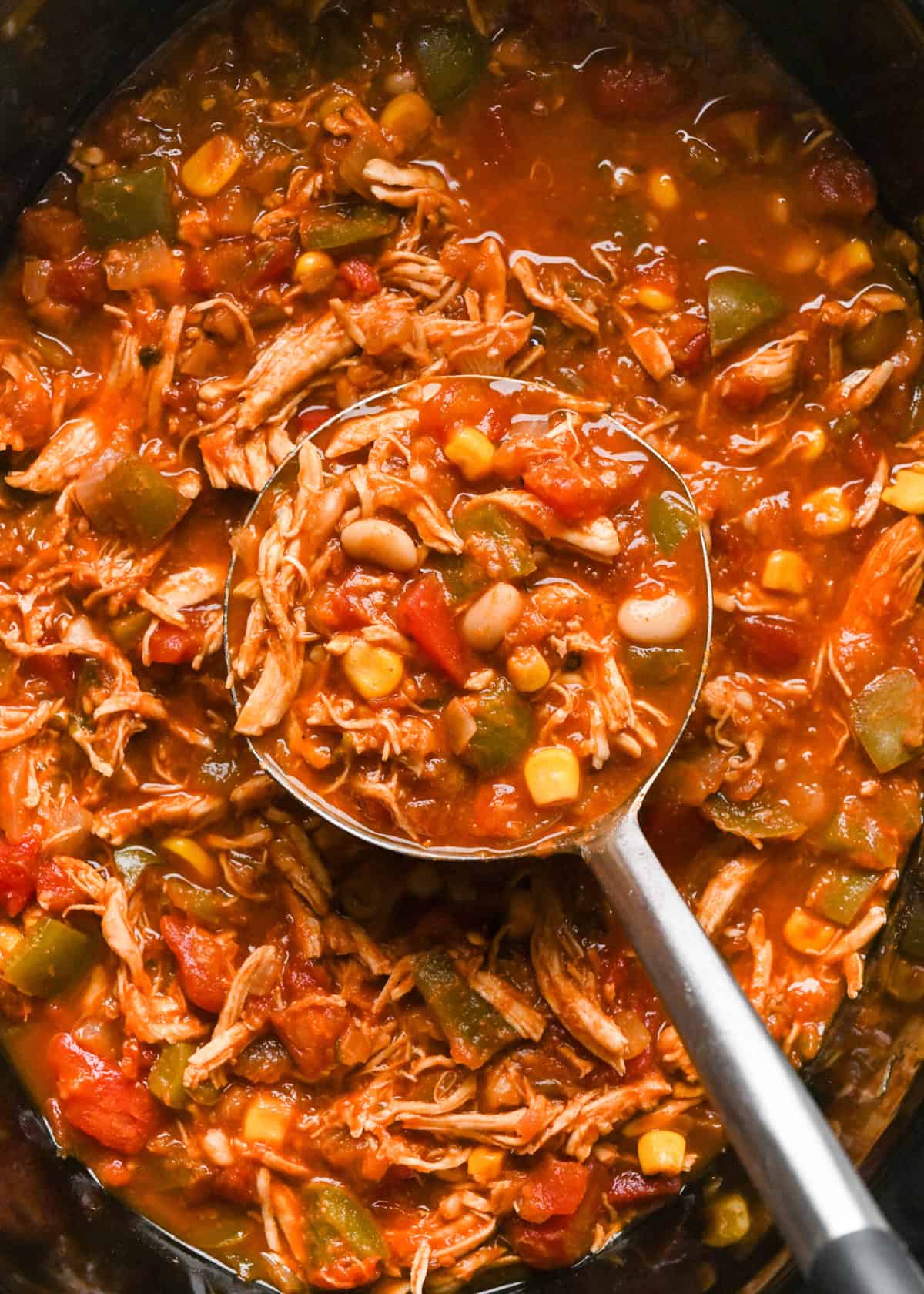 a spoon taking a scoop of Slow Cooker Chicken Chili in a crock pot