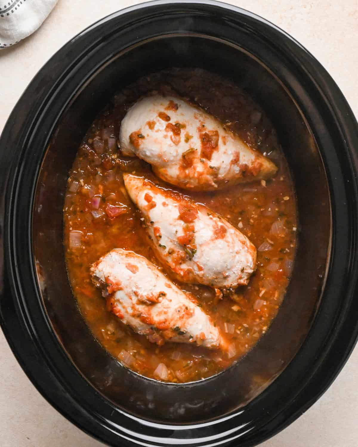 3 cooked chicken breasts in salsa in a crock pot making Slow Cooker Chicken Chili