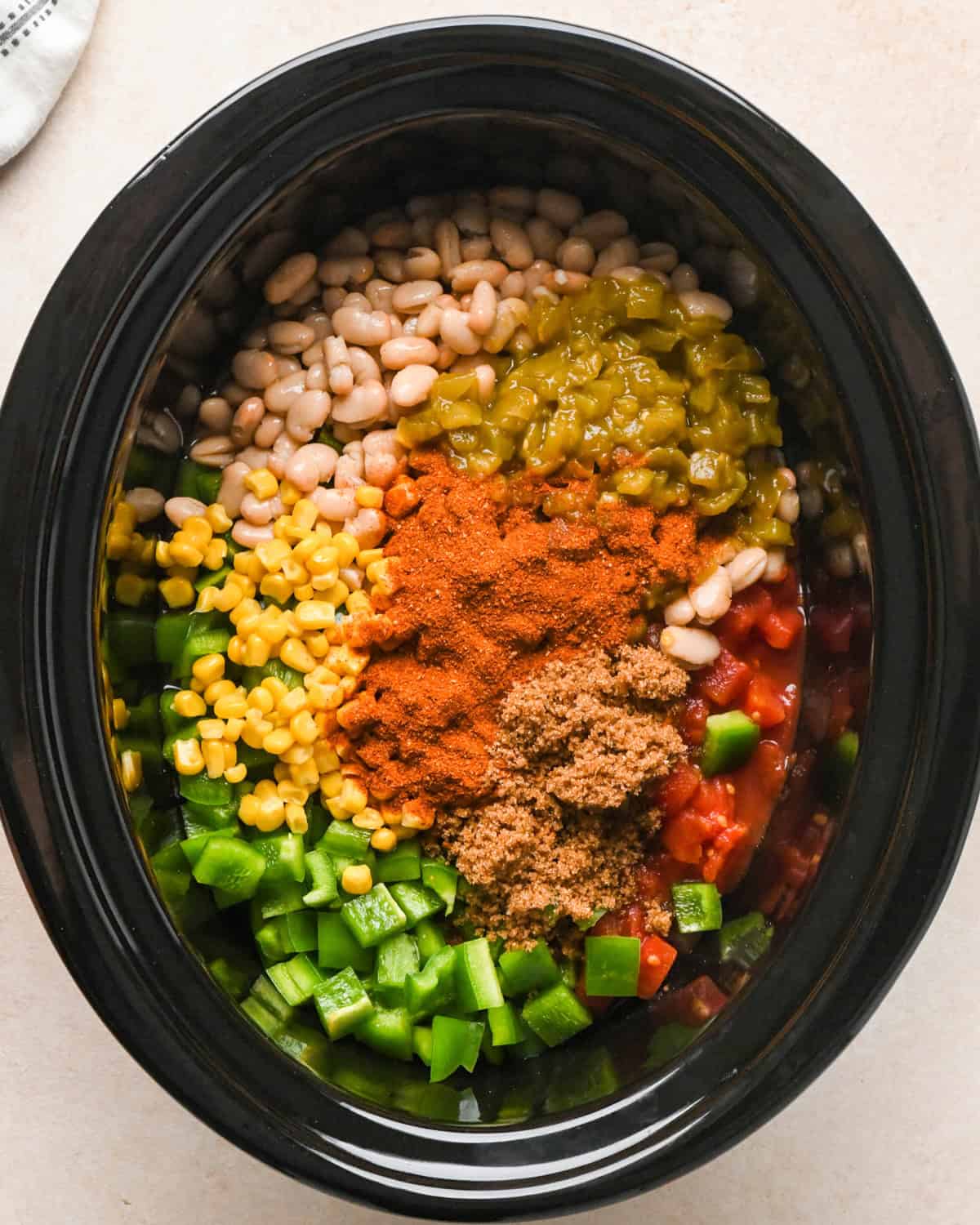 beans, green chiles, corn, tomatoes, chili seasoning, green pepper and brown sugar added to a crockpot making Slow Cooker Chicken Chili