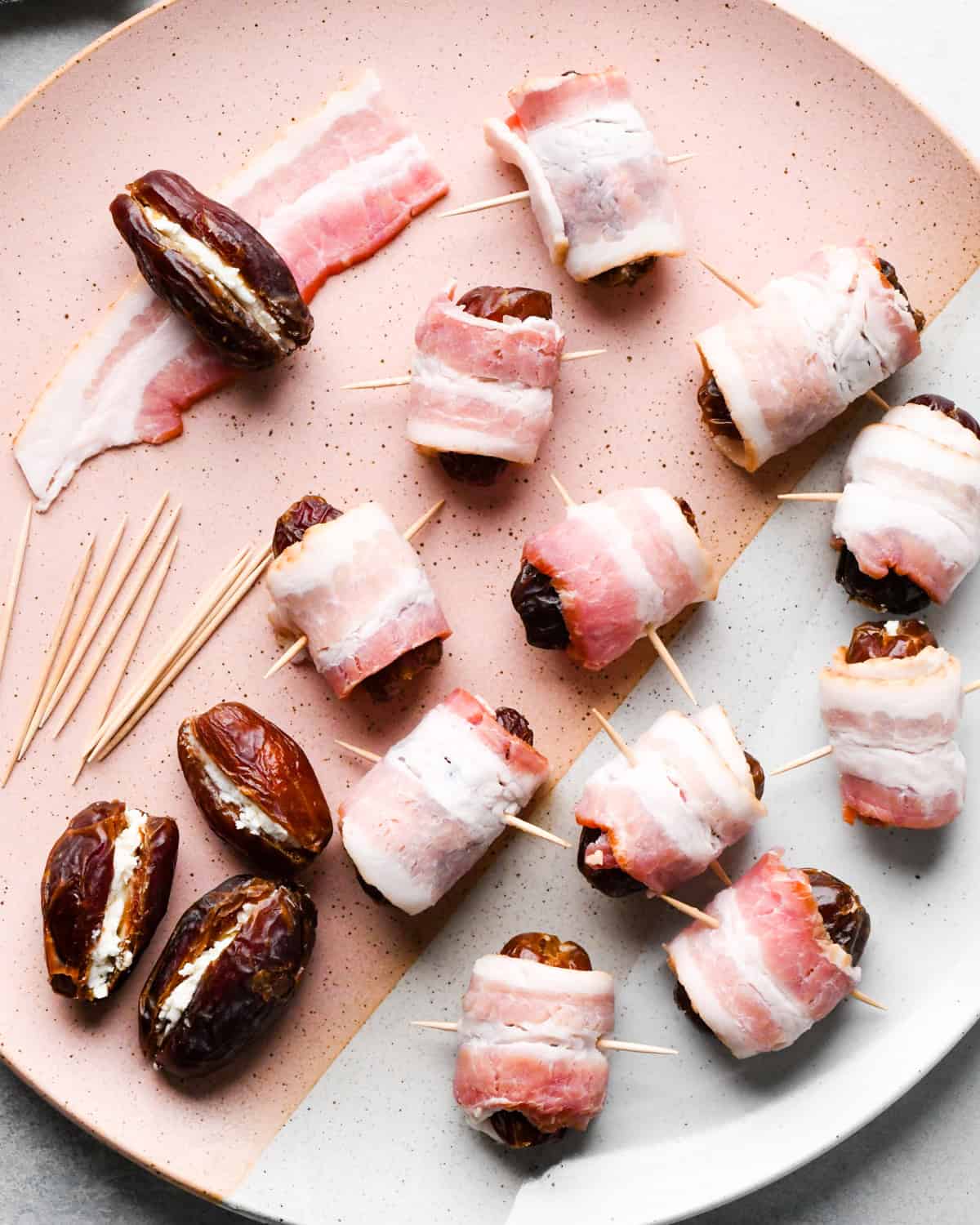 Making bacon-wrapped dates: overhead photo of bacon-wrapped dates, each one secured with a toothpick and arranged on a speckled plate.