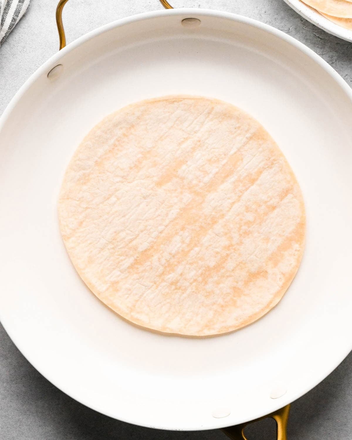 making breakfast quesadillas - a tortilla in a white skillet