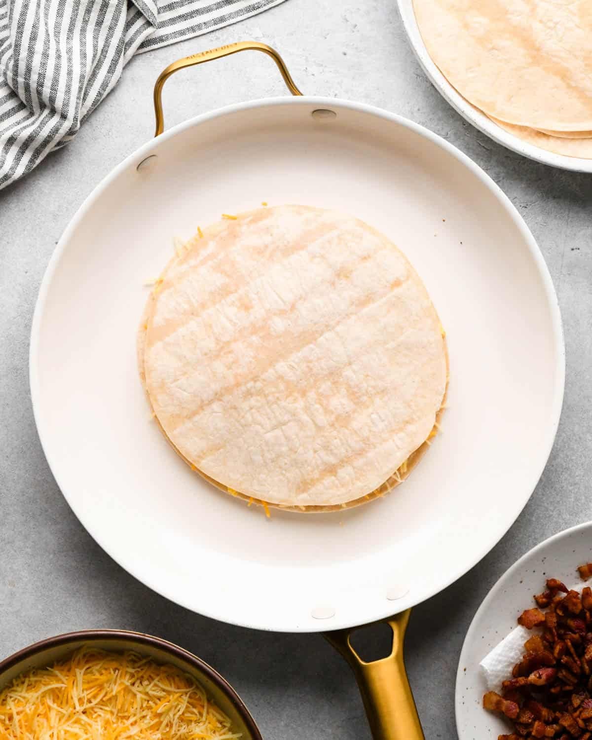making breakfast quesadillas - an assembled breakfast quesadilla in a white skillet not cooked yet