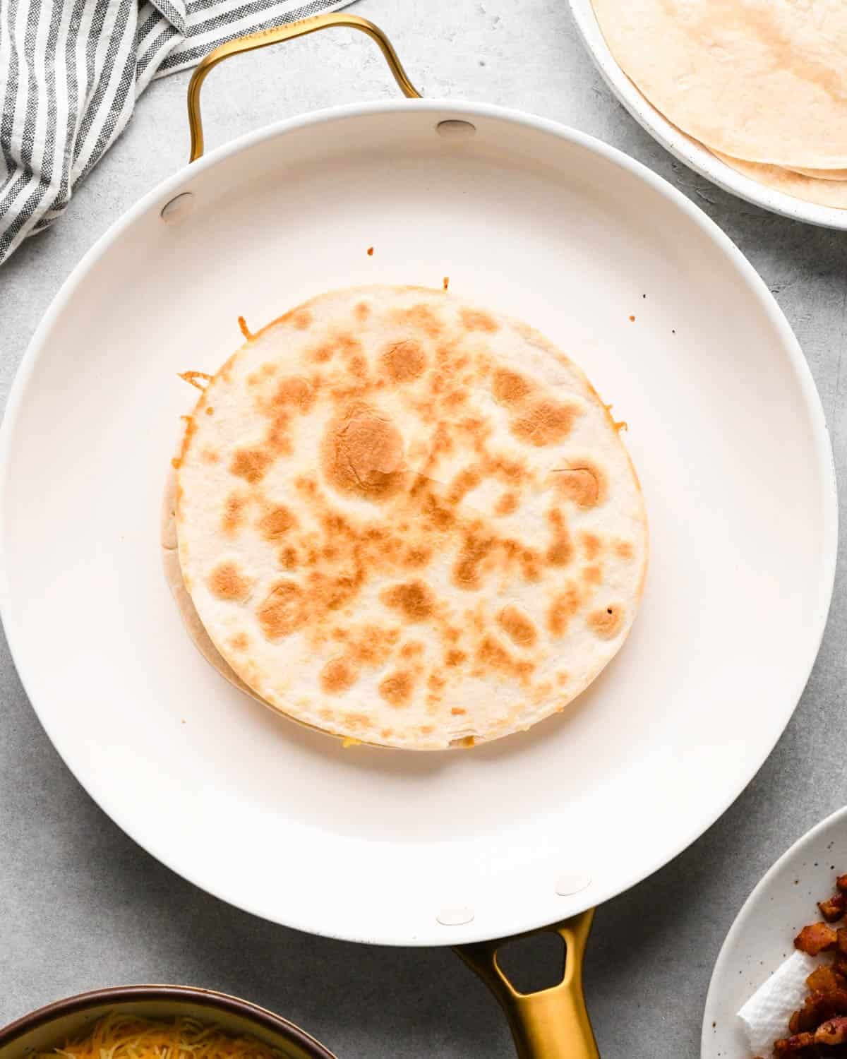 a cooked breakfast quesadilla in a white skillet