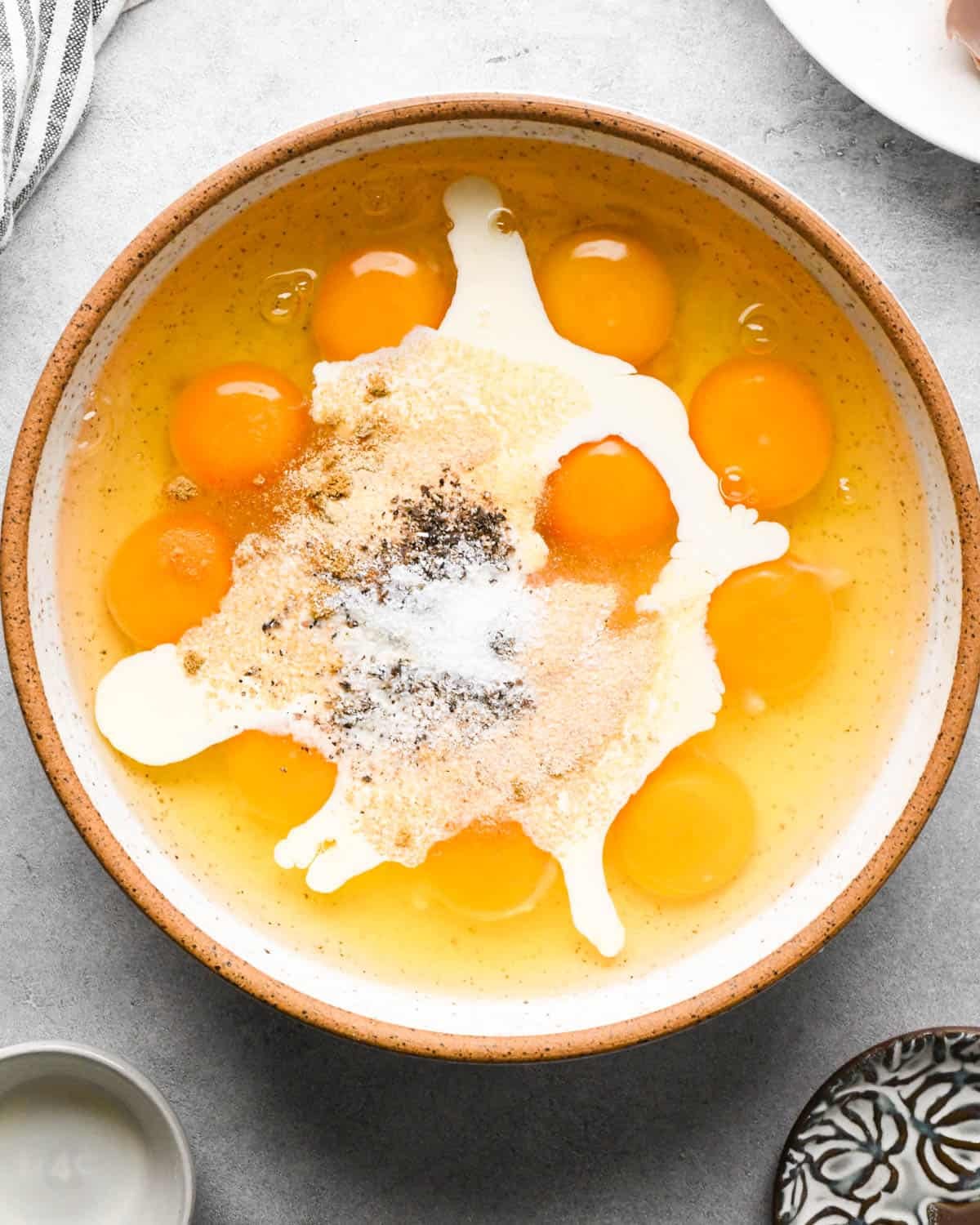 making breakfast quesadillas - eggs, heavy cream, and spices in a ceramic bowl before whisking