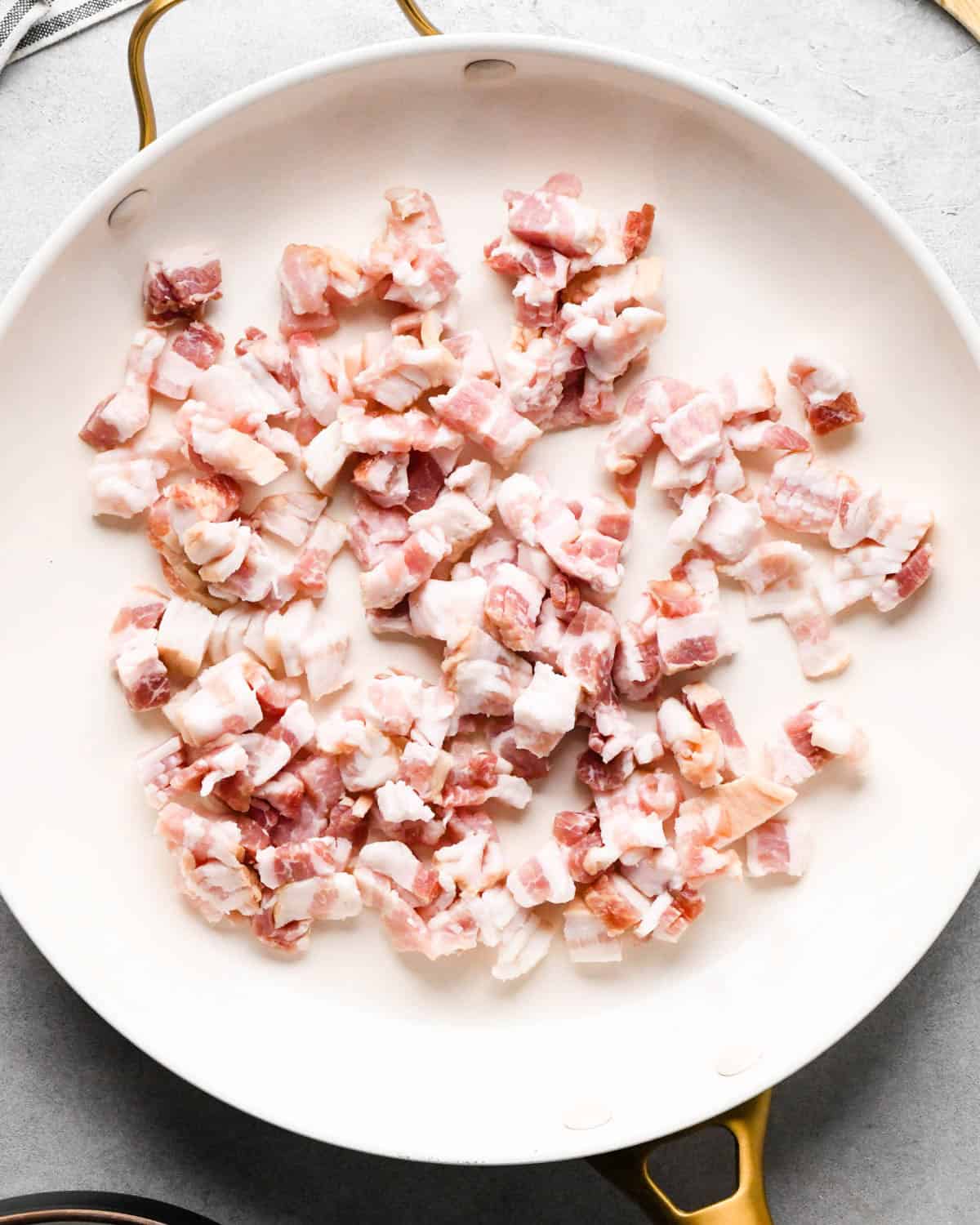 making breakfast quesadillas - uncooked bacon diced in a white skillet