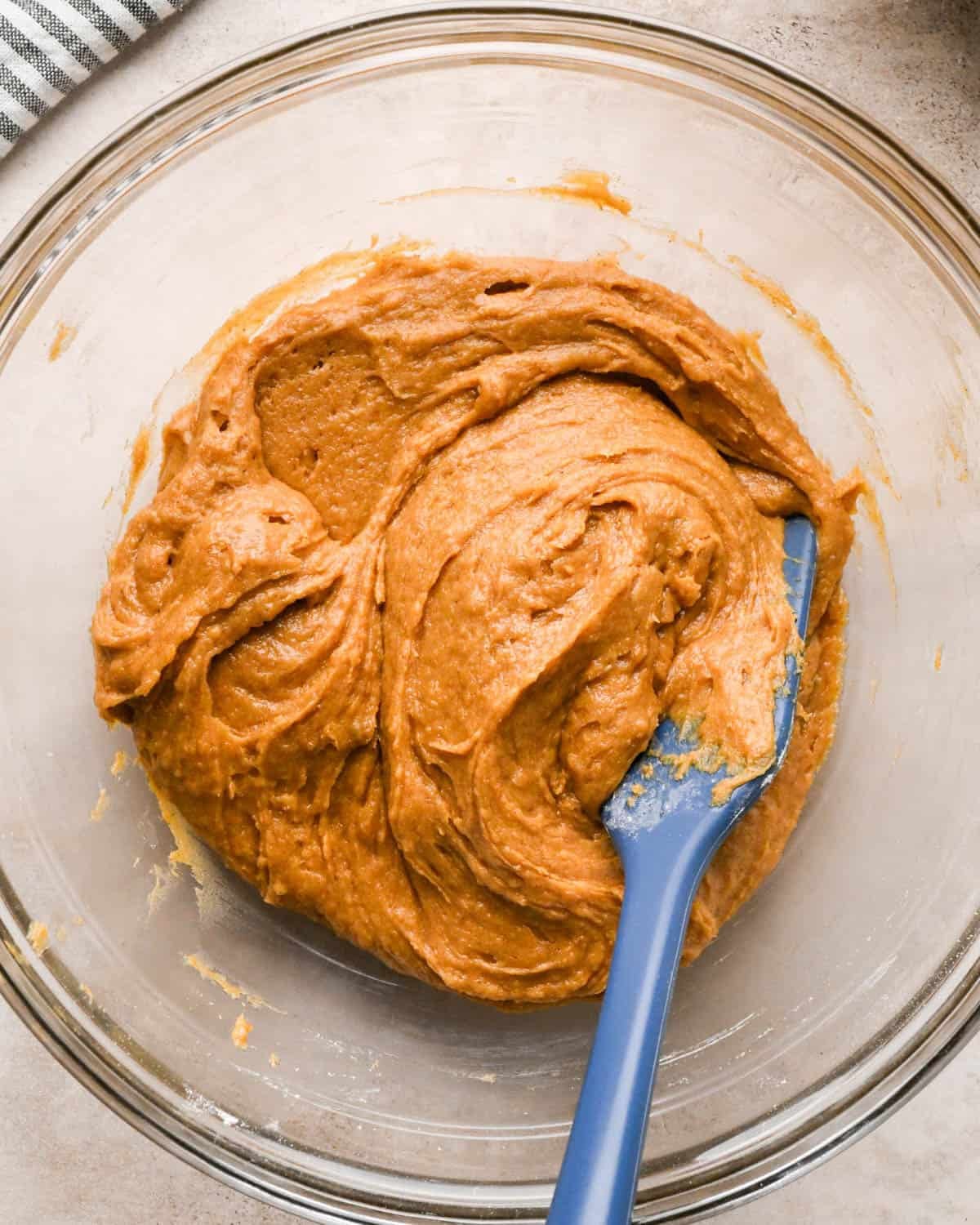 making brown butter pumpkin cookies - dough in a glass mixing bowl with a blue spatula