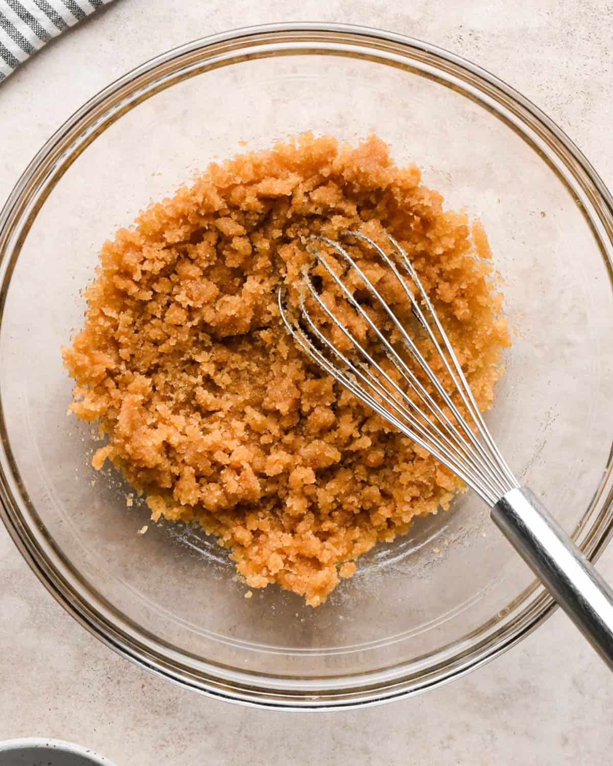 making brown butter pumpkin cookies - butter and sugars mixed together in a glass mixing bowl with a metal whisk in the bowl too