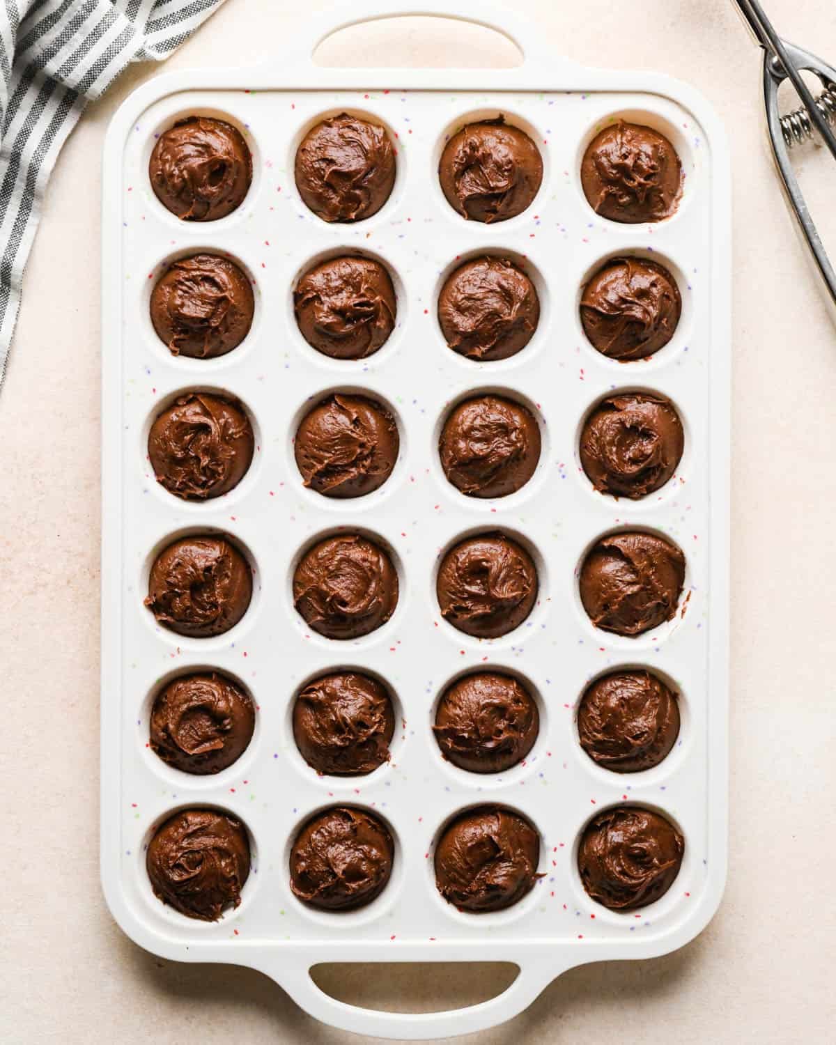 24 brownie bites in a white silicone baking pan before baking