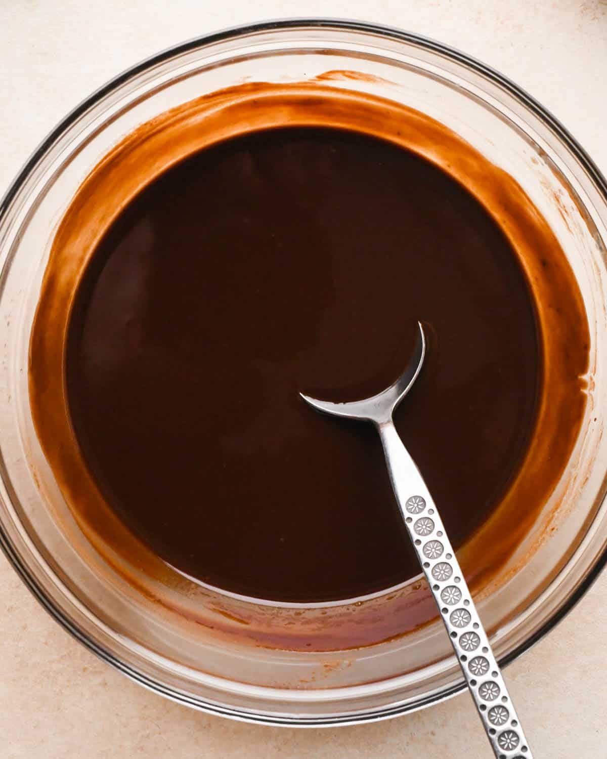making brownie bites - melted chocolate and butter in a glass bowl with a metal spoon