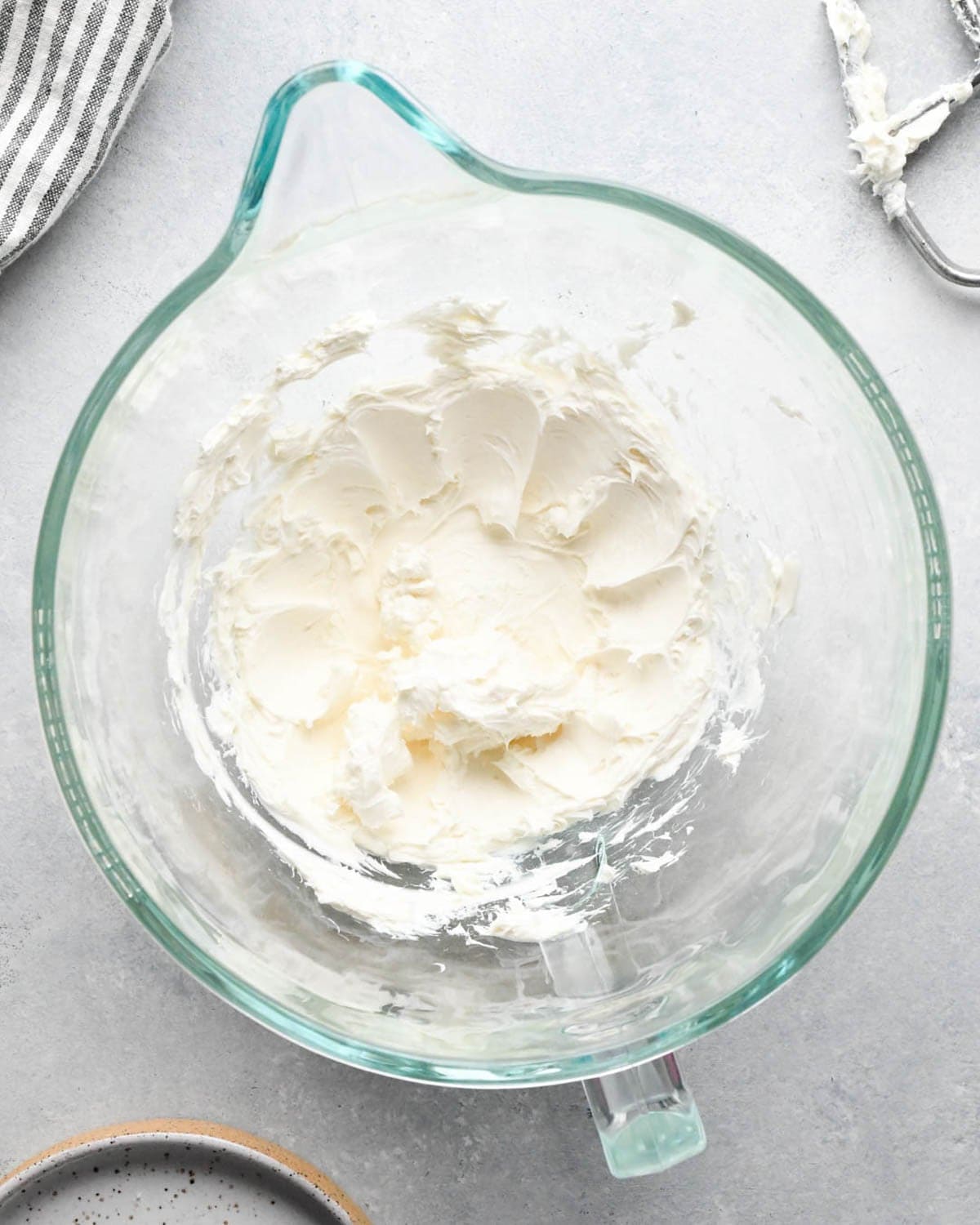 making caramel cream cheese apple dip - cream cheese in a glass mixing bowl after being beaten