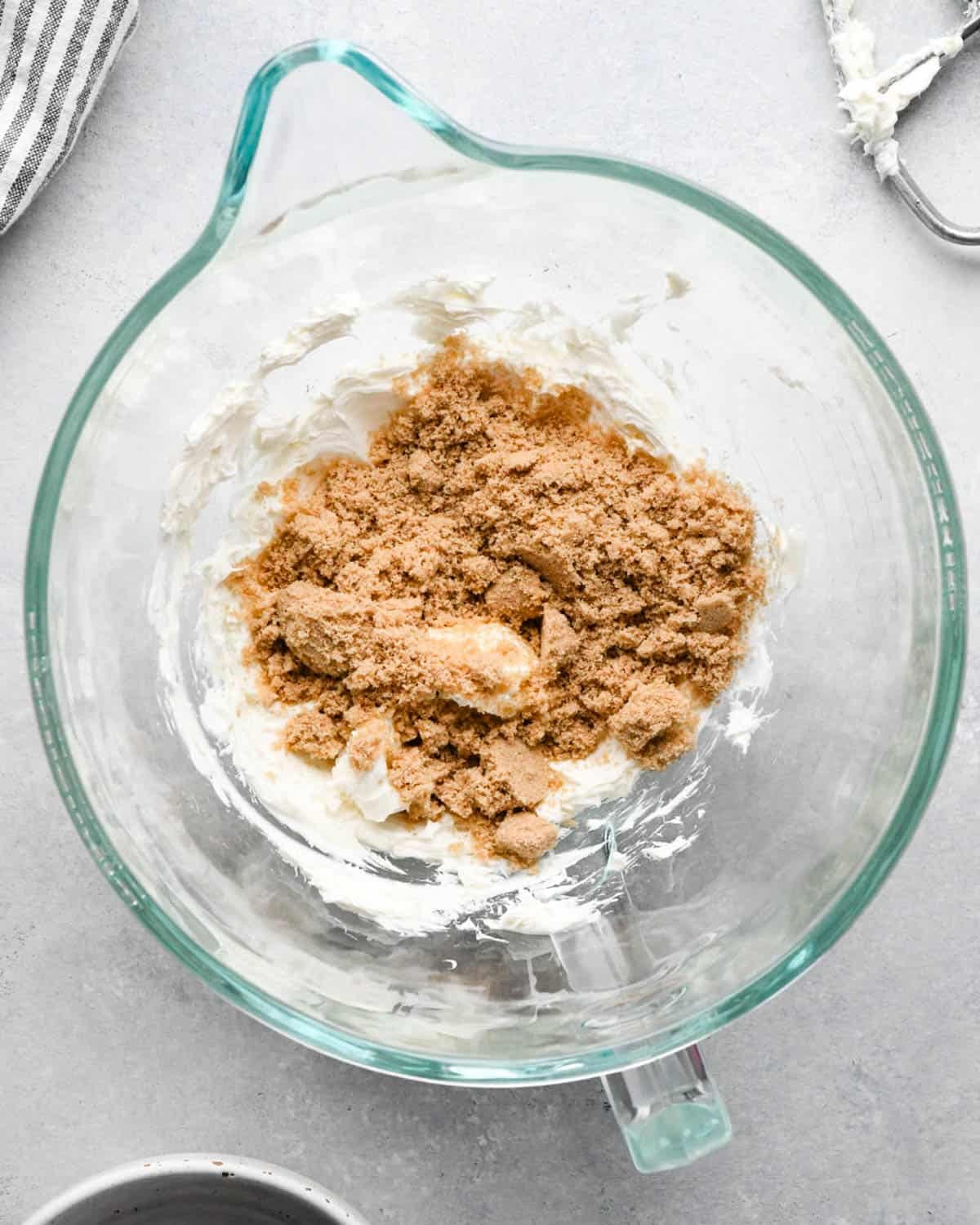 making caramel cream cheese apple dip - brown sugar added to the cream cheese in a glass mixing bowl before beating