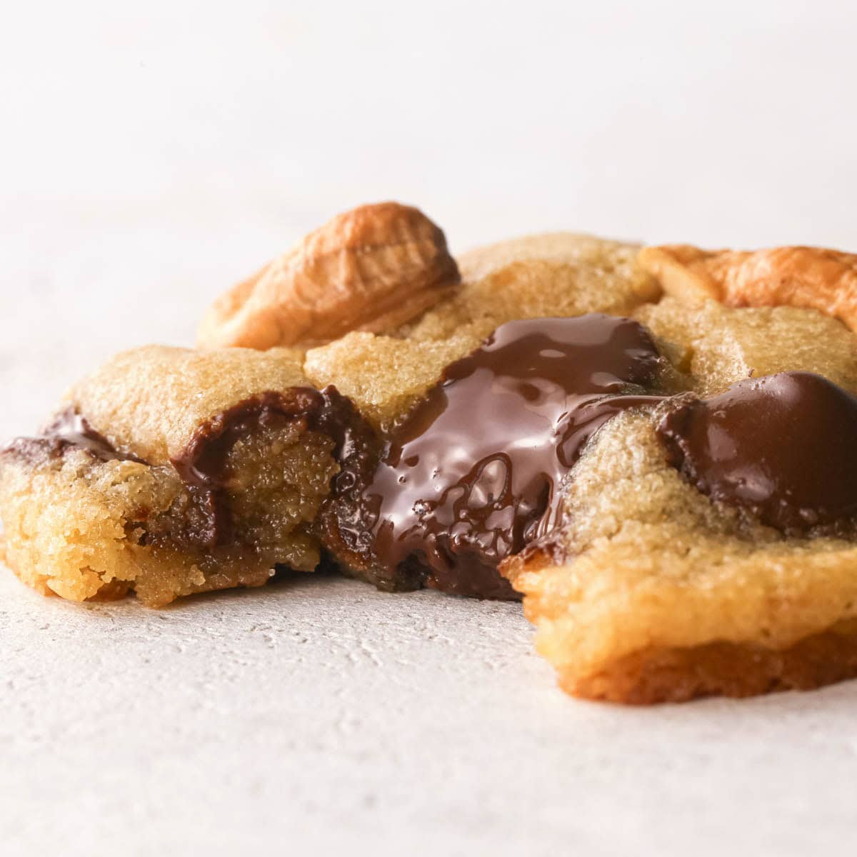 Up-close photo of a chocolate chip cashew cookie with a bite taken out of it to show the melty chocolate, the crispy outside, and the chewy, perfectly gooey inside of the cookie.