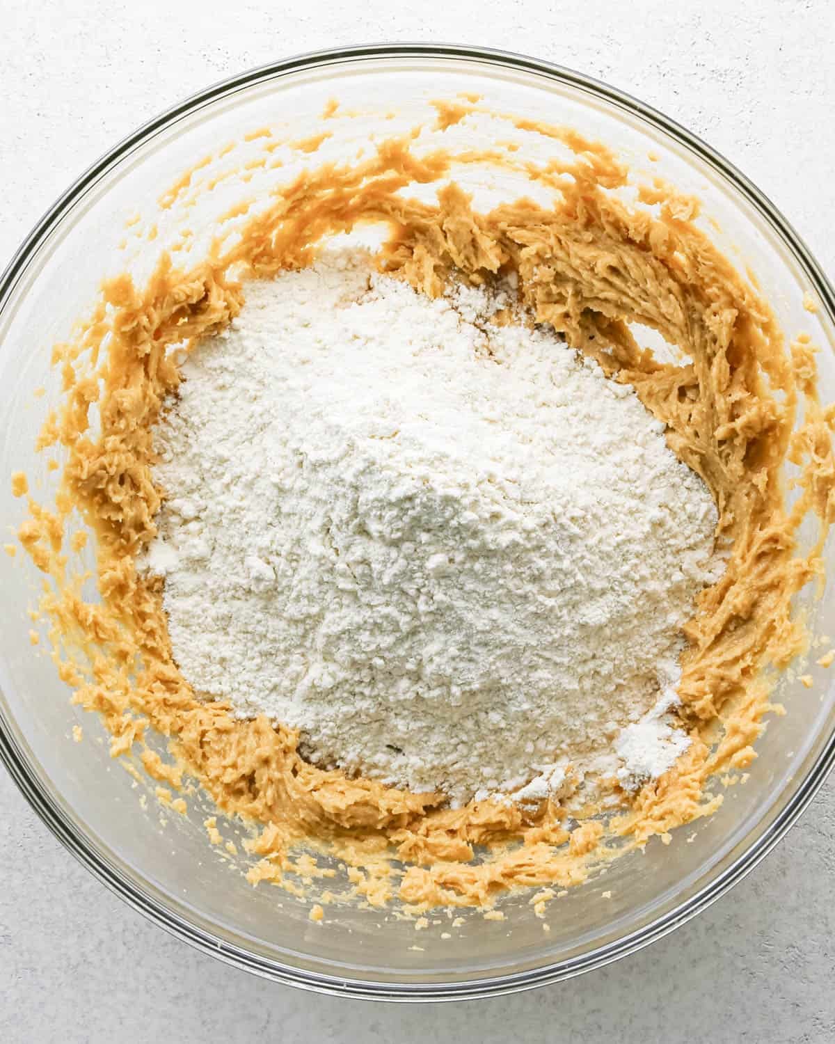 Making chocolate chip cashew cookies: overhead photo of dry ingredients for cashew cookies being added to the bowl with wet ingredients.