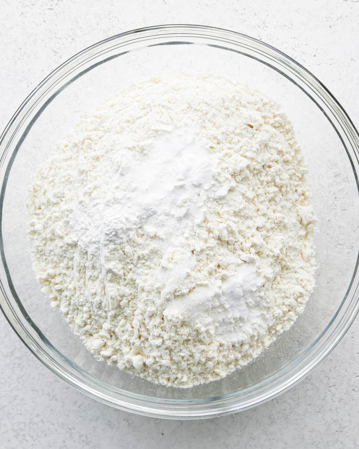 Making chocolate chip cashew cookies: overhead photo of the dry ingredients for cashew cookies in a large clear mixing bowl.