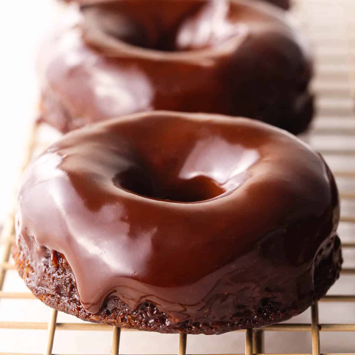 two donuts with chocolate glaze on them on a wire cooling rack