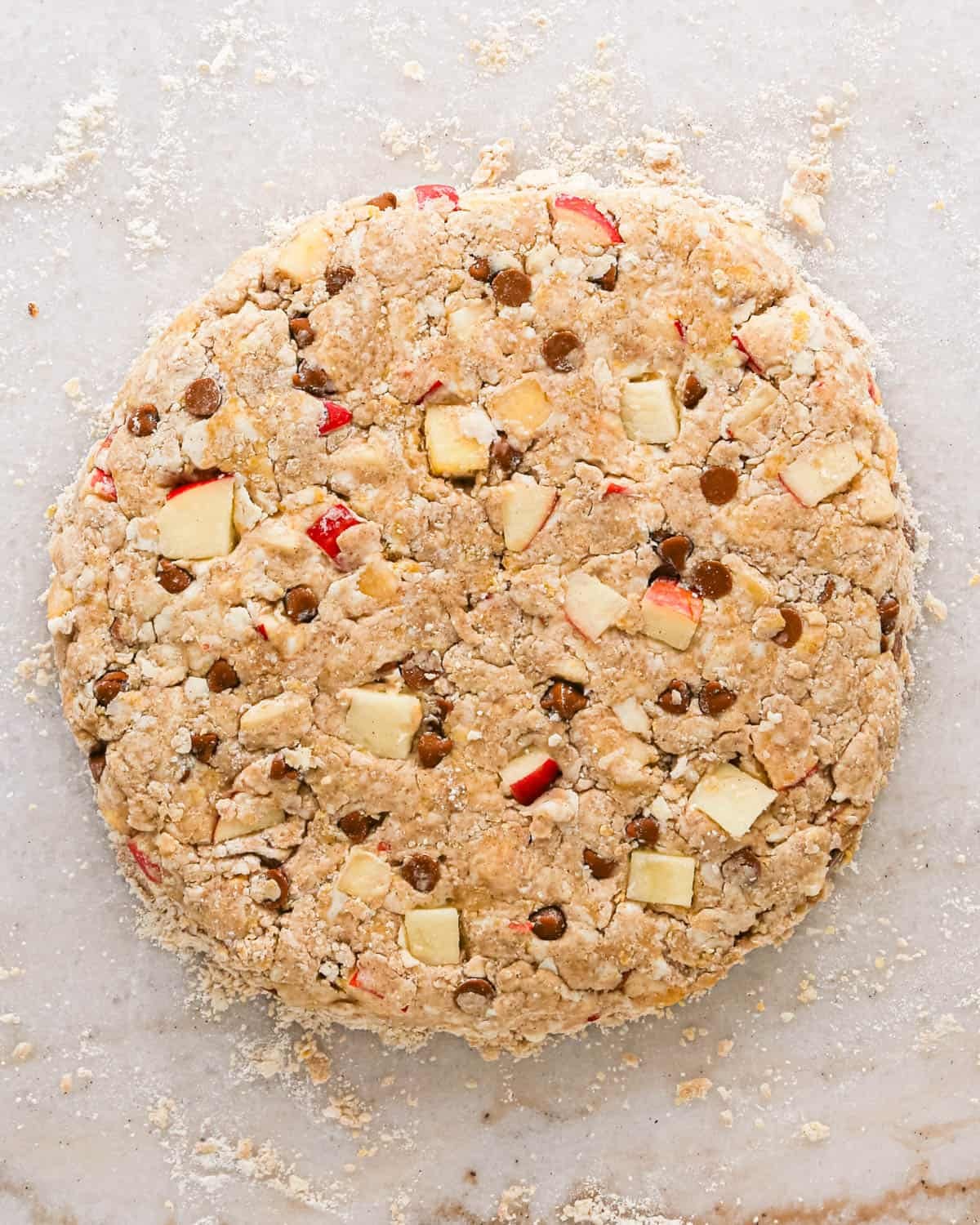 apple scones dough formed into a round disc on a marble surface