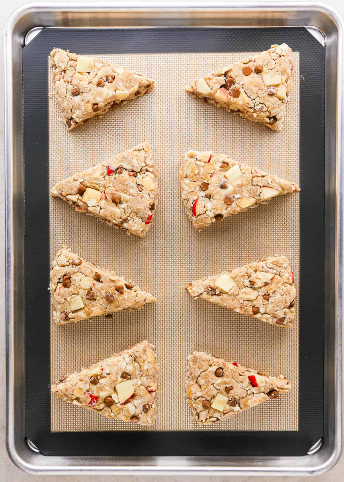 8 apple scones on a baking sheet lined with a silicone baking mat