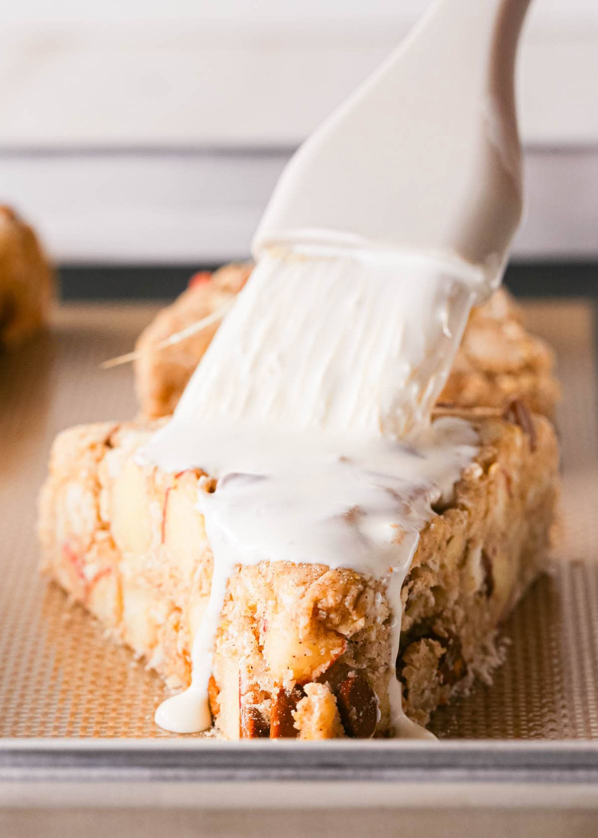 heavy cream being brushed over the top of an apple scone