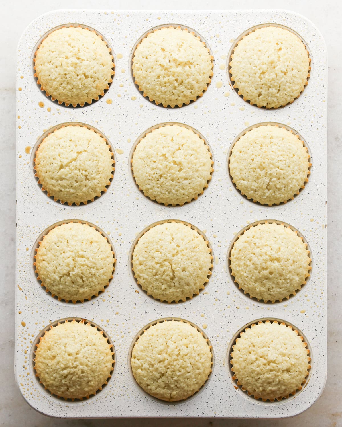 Making coconut cupcakes: overhead photo of completed, baked cupcakes sitting in a 12-cup muffin tin.