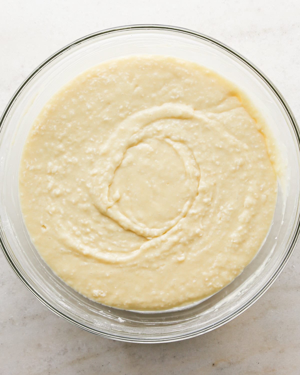 Making coconut cupcakes: overhead photo of completed cupcake batter in a clear mixing bowl and ready to scoop.