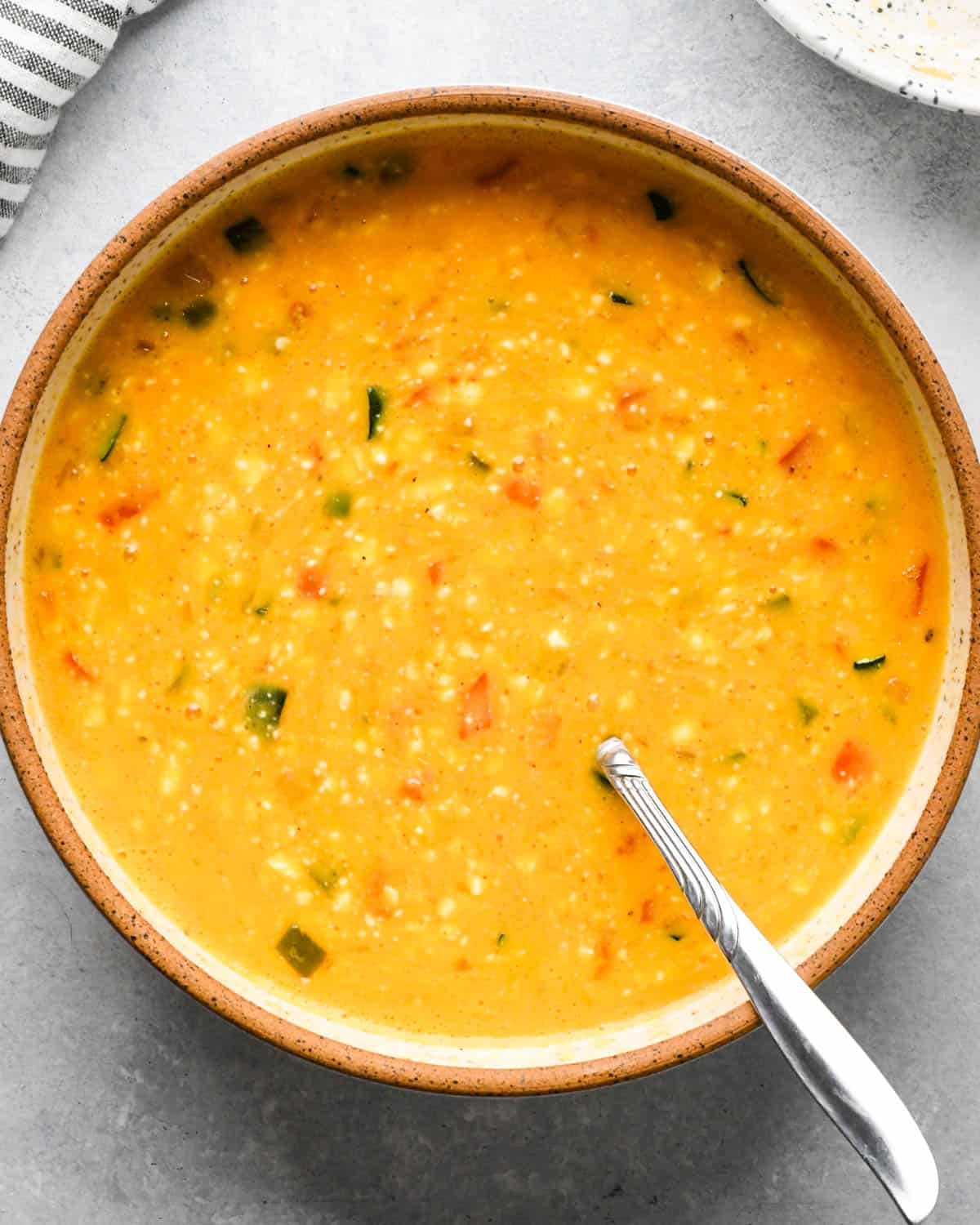 making cottage cheese egg bites - egg and vegetable mixture in a bowl with a metal spoon