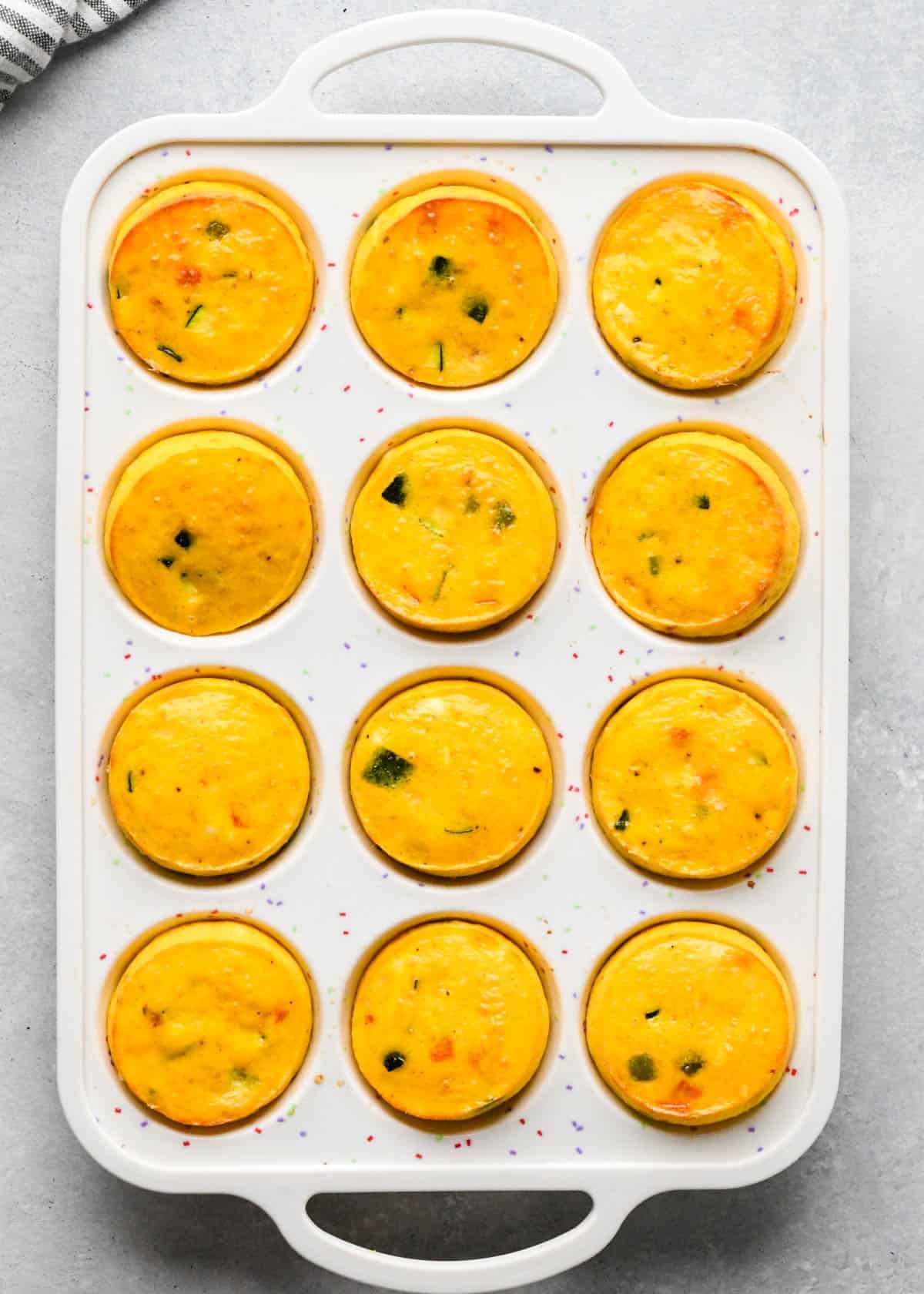 vegetable cottage cheese egg bites mixture in a white silicone muffin pan after baking