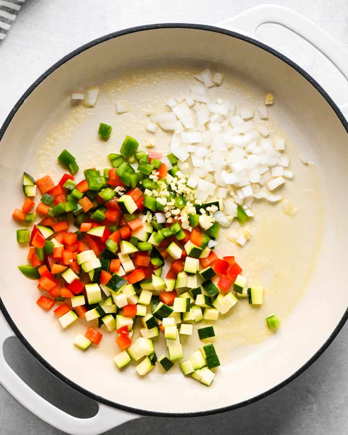 making cottage cheese egg bites - green bell peppers, red bell peppers, zucchini and onions all diced in a saute pan with minced garlic and melted butter before cooking