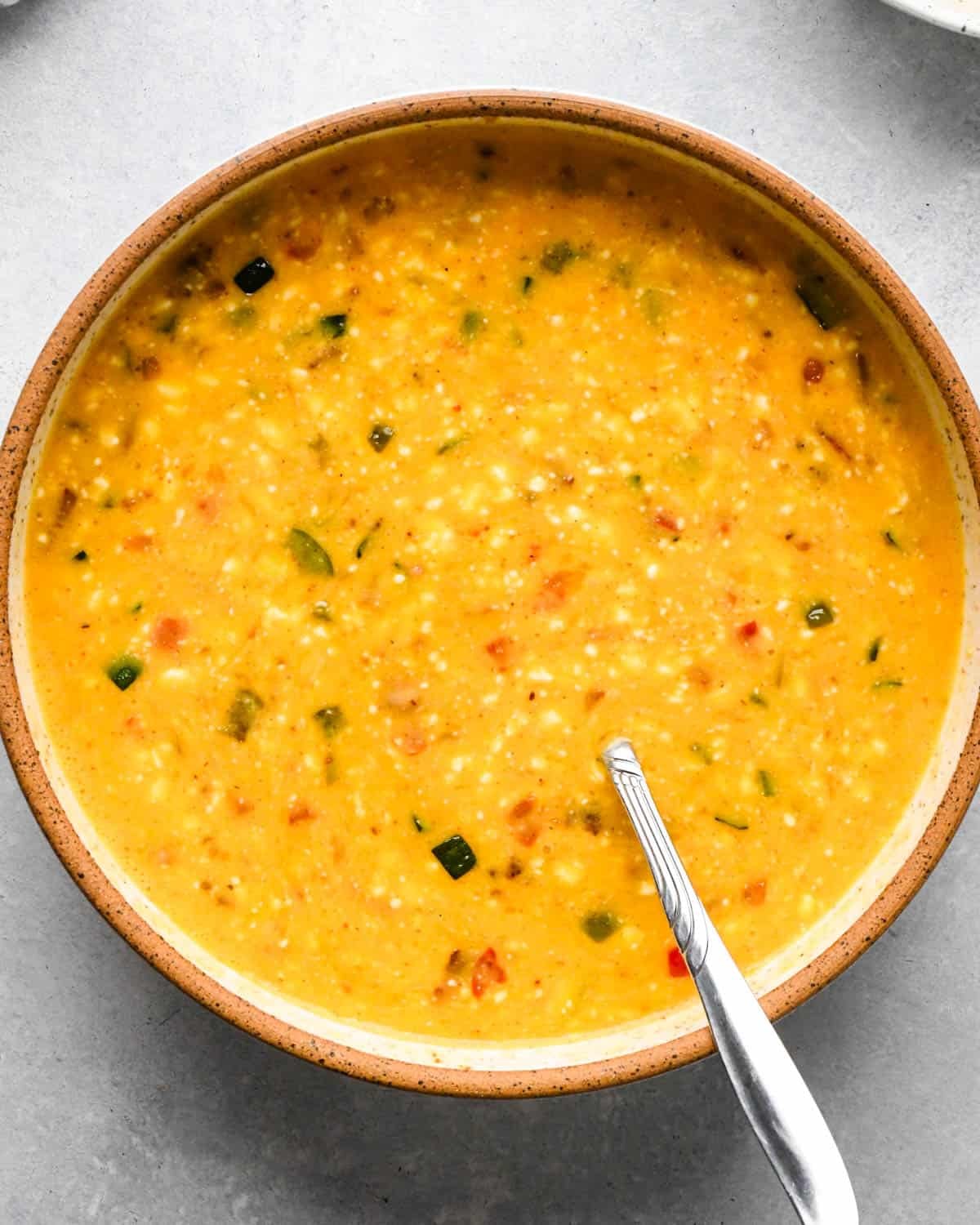 making cottage cheese egg bites - bacon and vegetable mixture added to the egg mixture after stirring in a bowl with a metal spoon