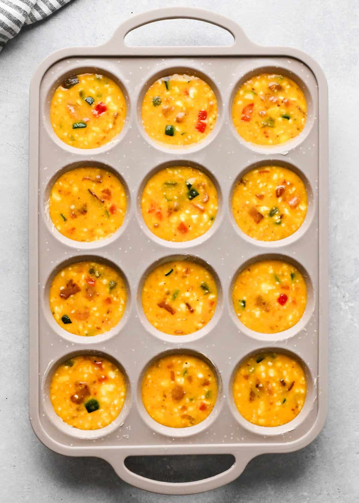 cottage cheese egg bites mixture in a tan/gray silicone muffin pan before baking