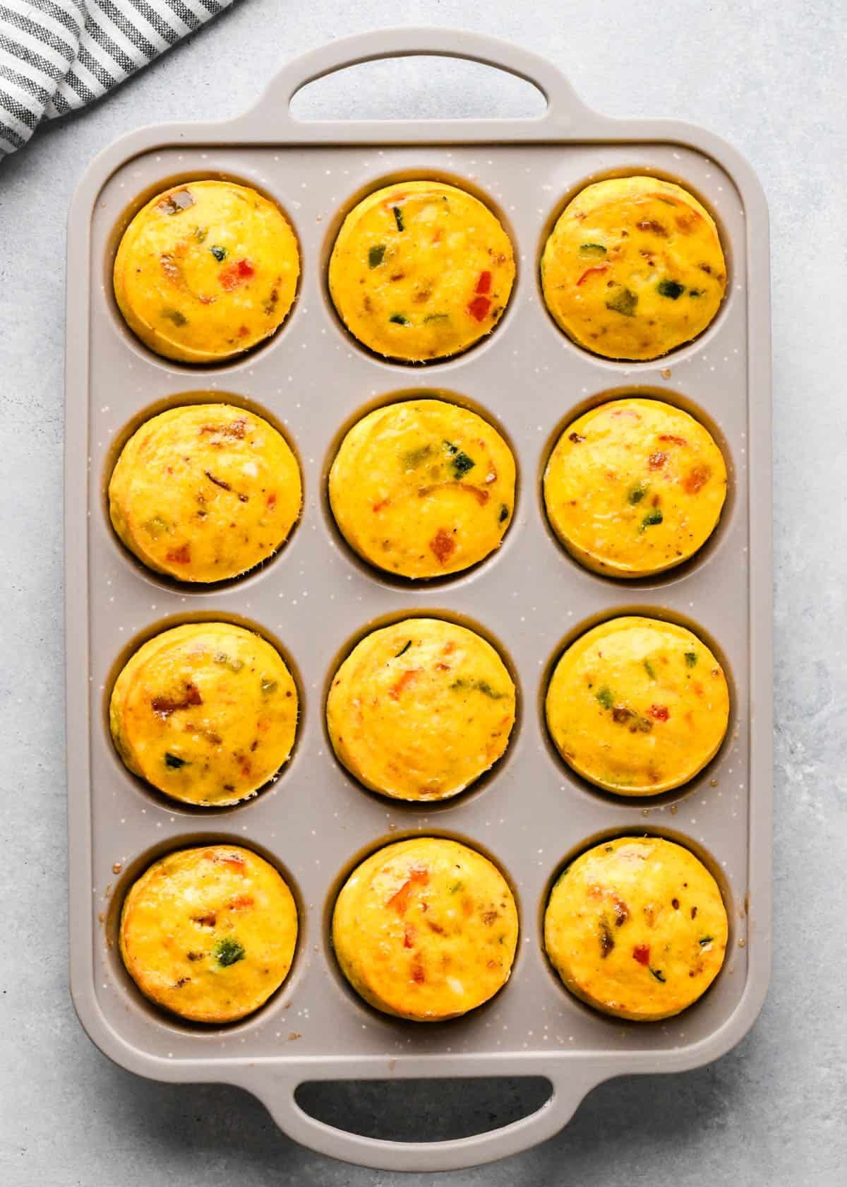 cottage cheese egg bites mixture in a tan/gray silicone muffin pan after baking
