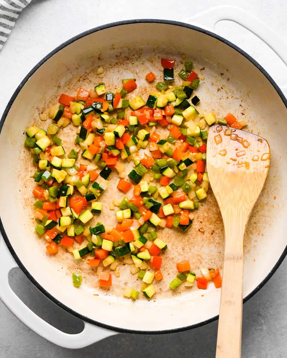 making cottage cheese egg bites - green bell peppers, red bell peppers, zucchini and onions all diced in a saute pan with minced garlic after cooking