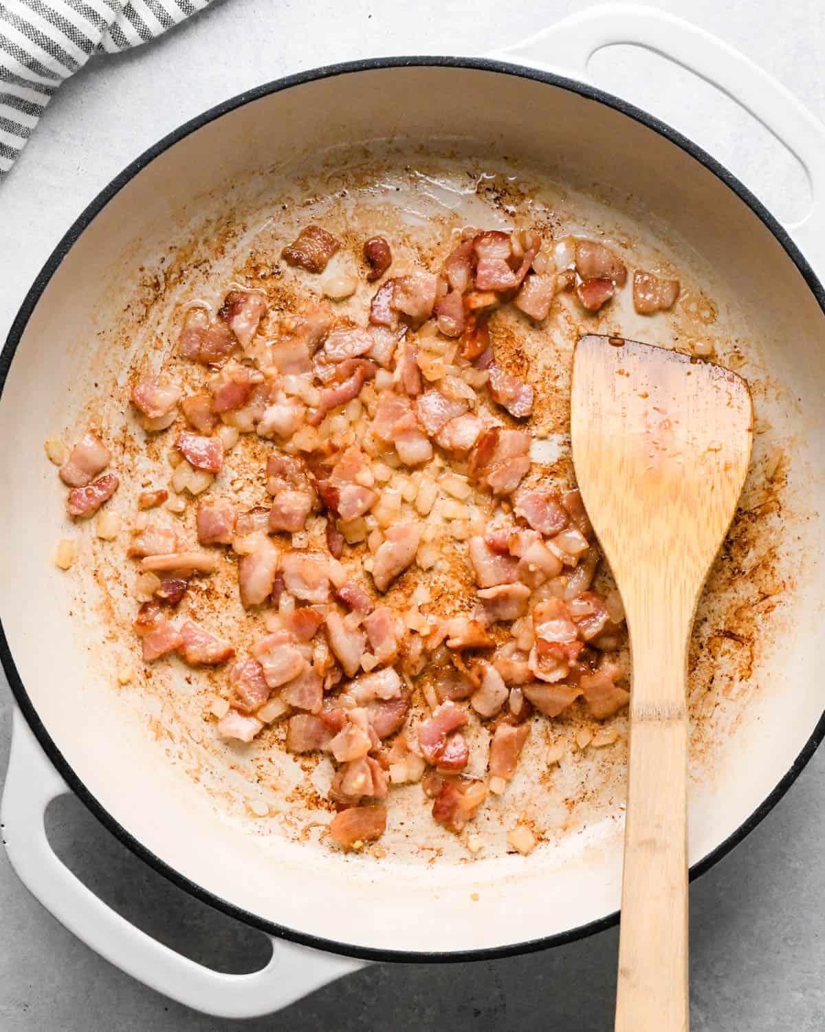 making cottage cheese egg bites - bacon onion and garlic cooked in a pan with a wooden spatula