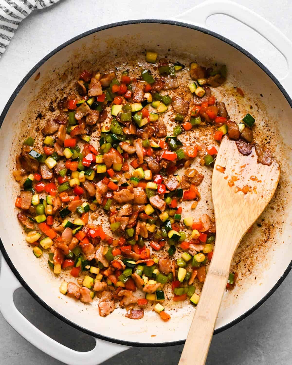 making cottage cheese egg bites - bacon and vegetables cooked in a pan with a wooden spatula