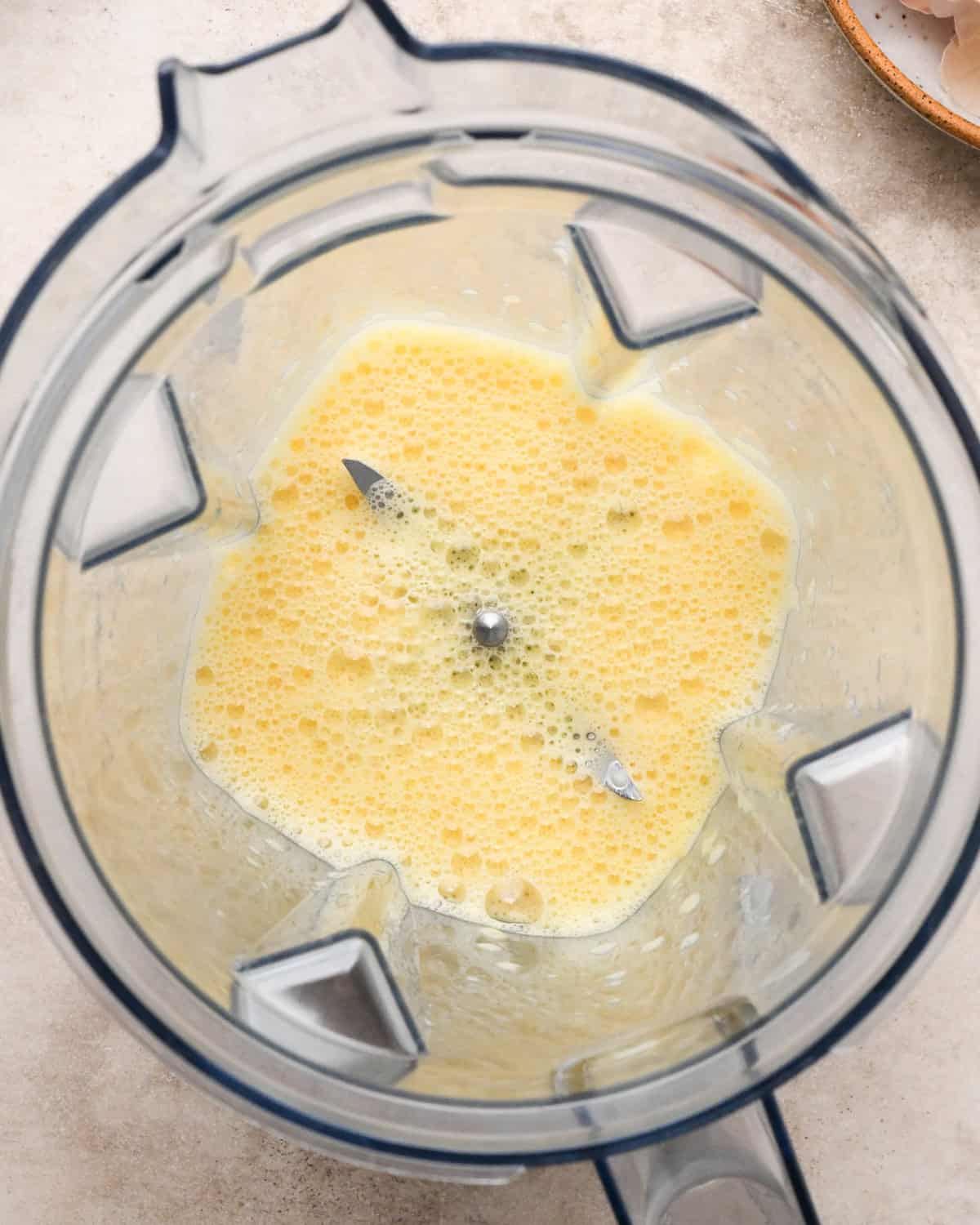 Making a Dutch baby: overhead view of eggs cracked into a blender and blended together.