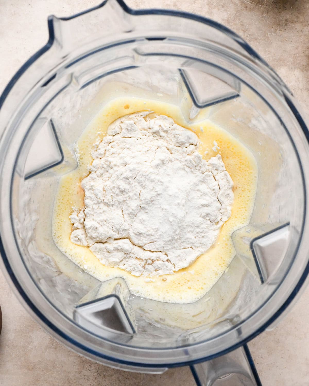 Making a Dutch baby: overhead view of dry ingredients being added to a blender with the beaten eggs.