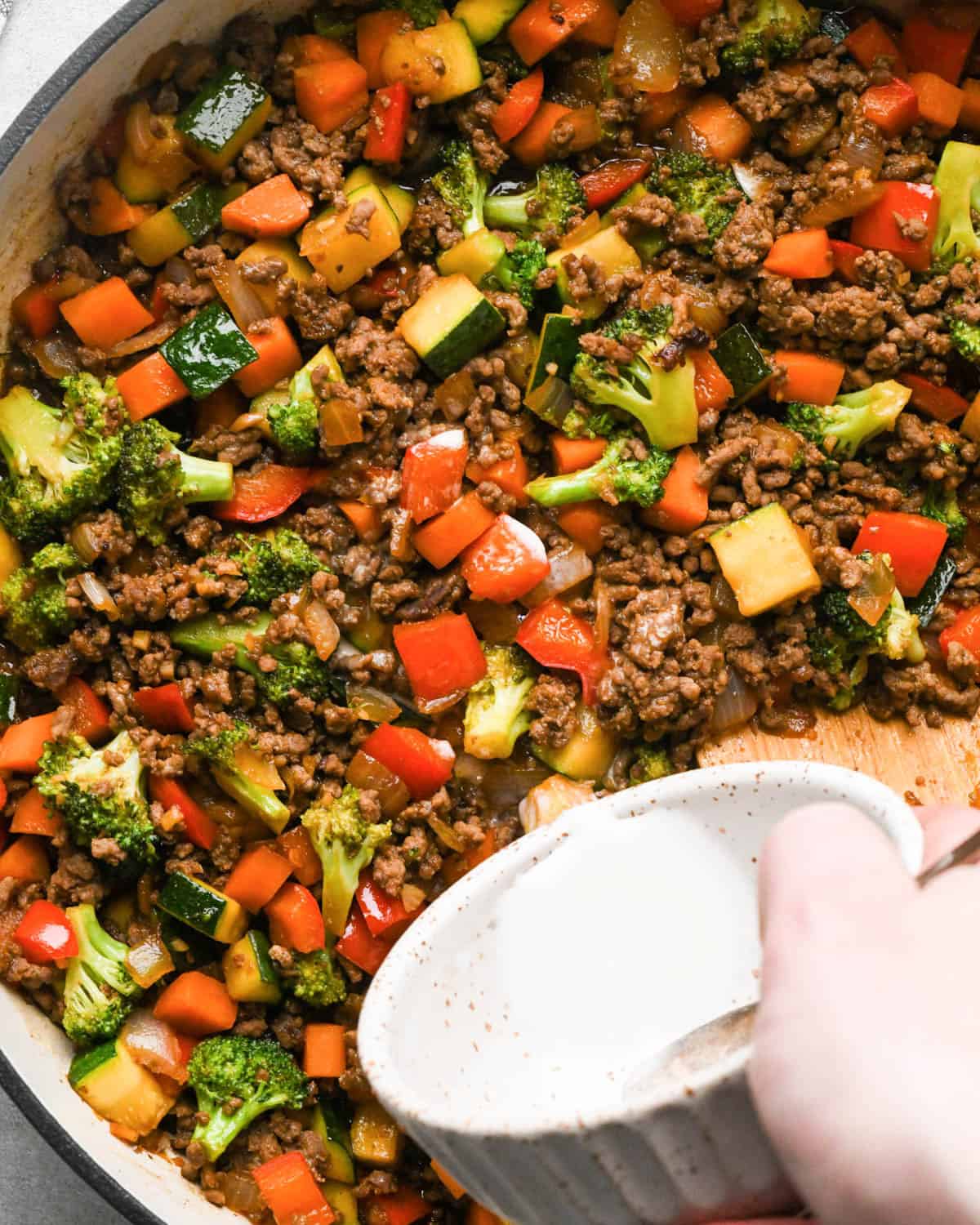 making ground beef stir fry - cornstarch mixture being added to the stir fry in a skillet